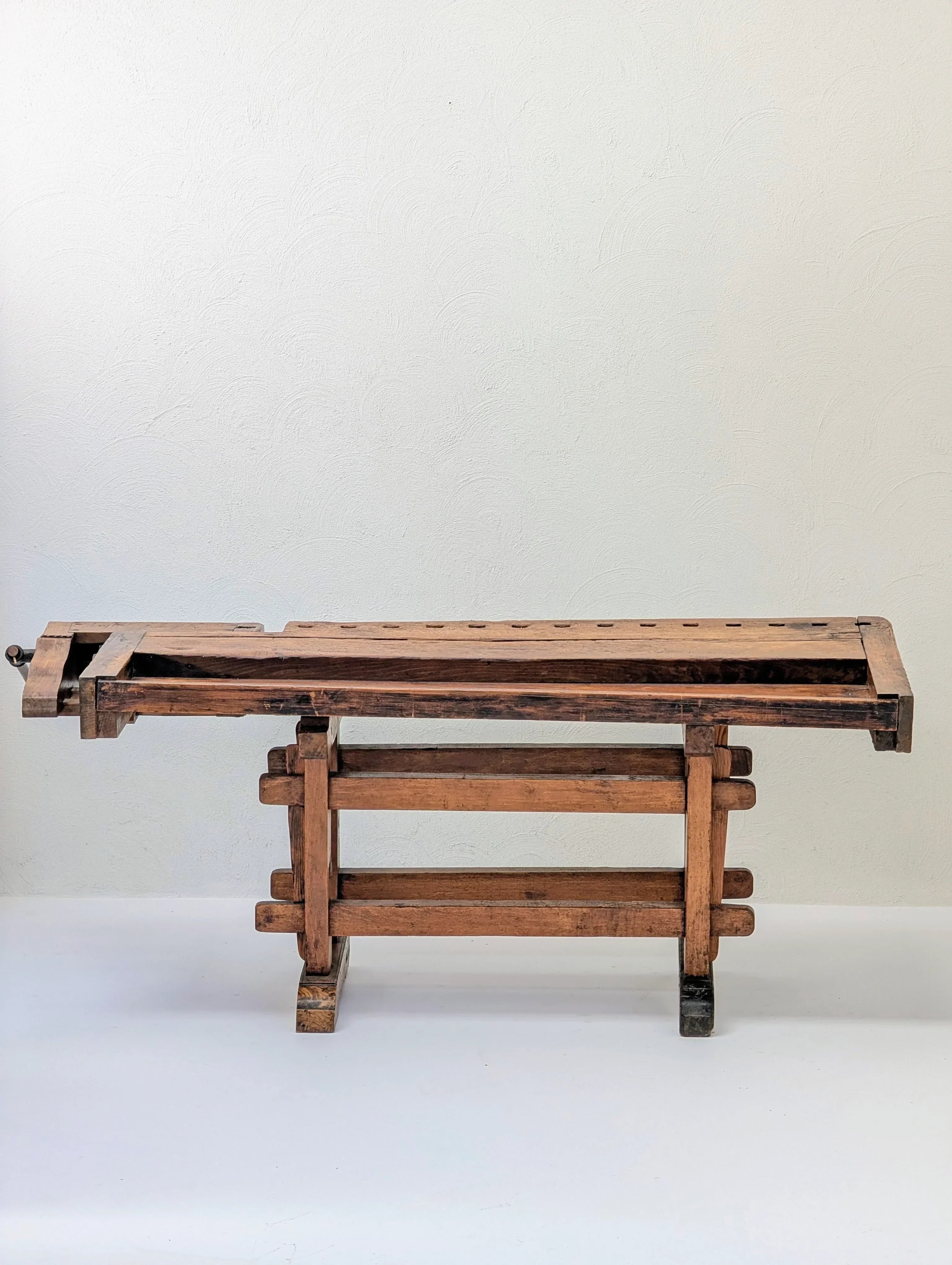 Vintage wooden workbench with vise against a plain white wall