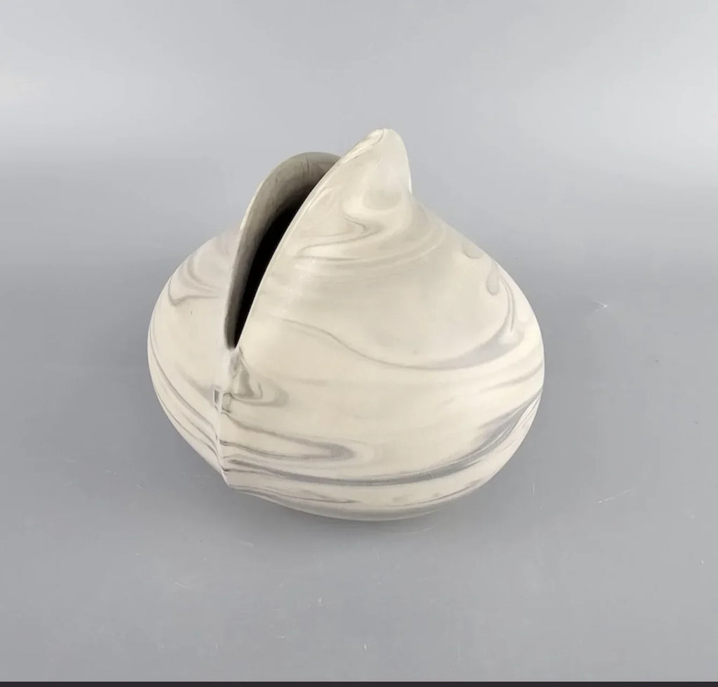 Marbled ceramic vase with organic shape on plain gray background