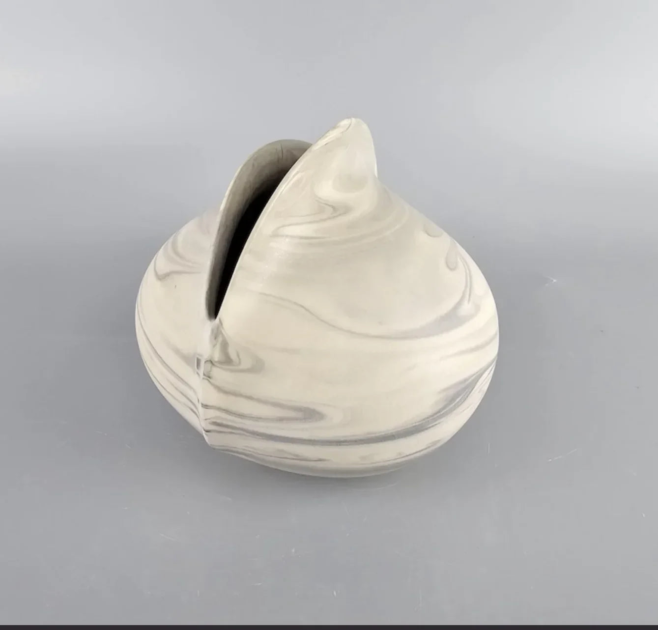 Marbled ceramic vase with organic shape on plain gray background