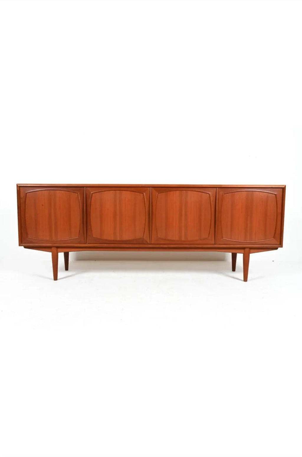 Mid-century modern teak sideboard with four paneled doors and tapered legs on white background