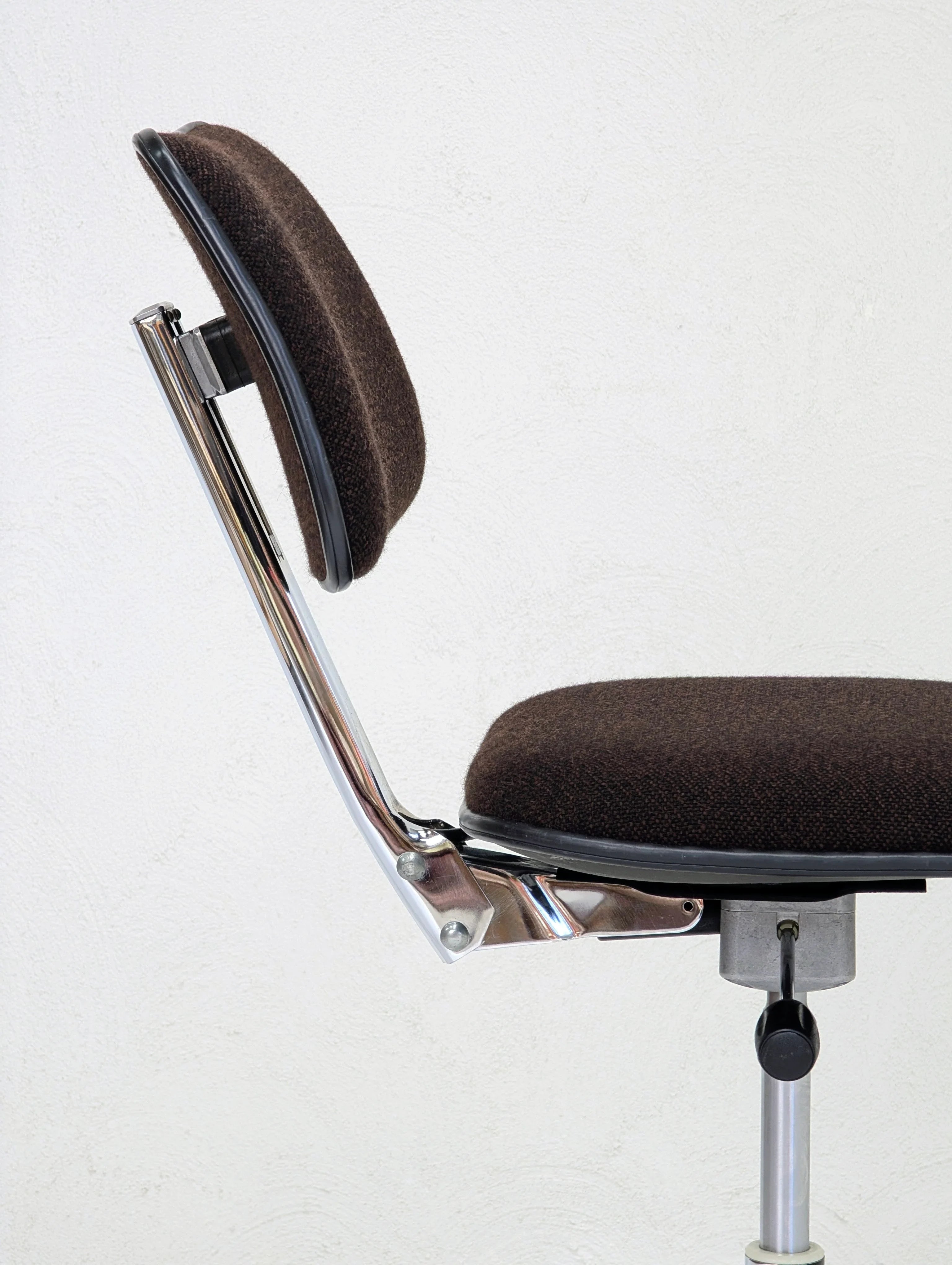 Side view of brown fabric office chair with chrome frame and adjustable height lever