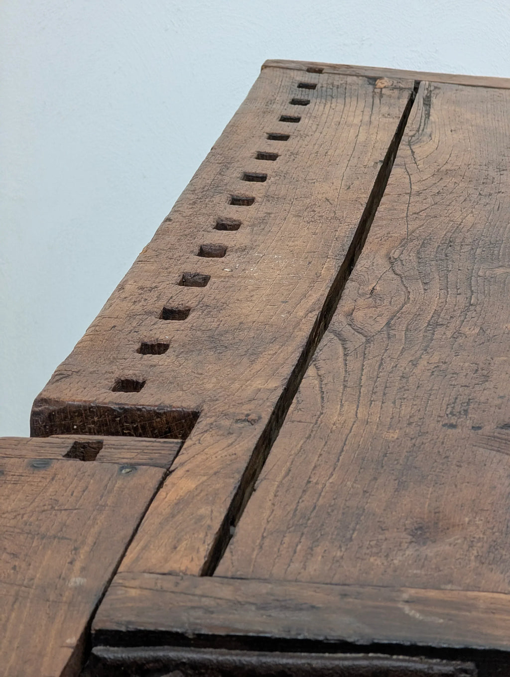 Close-up of rustic wooden table with square holes and visible wood grain texture