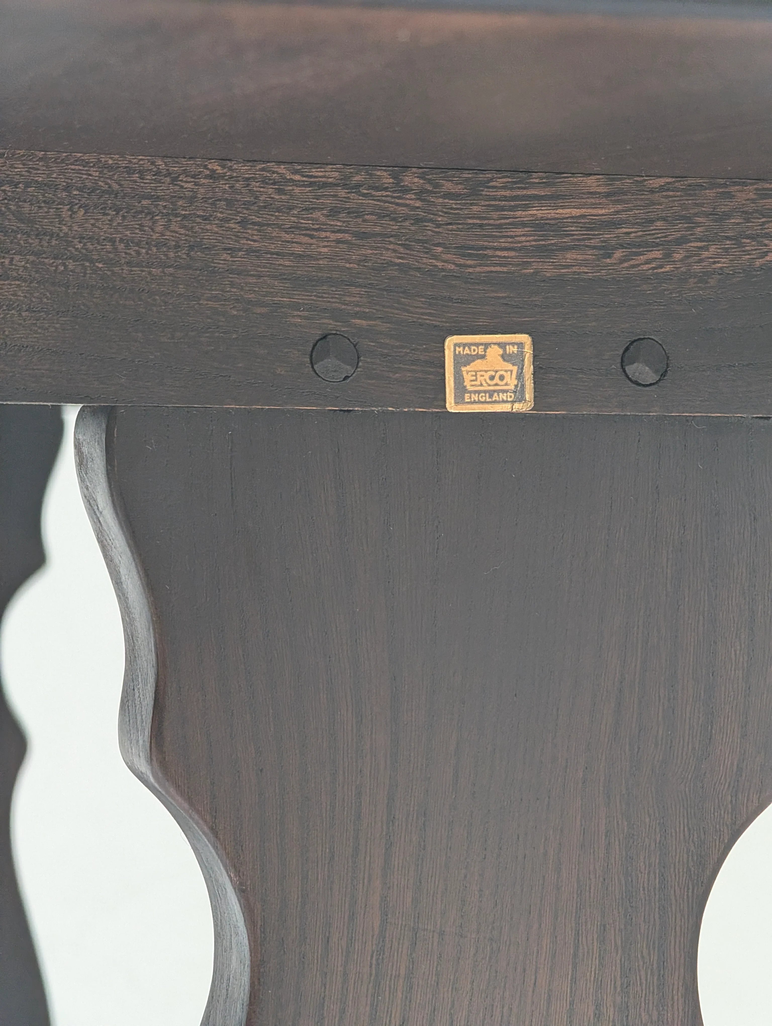 Close-up of dark wooden Ercol furniture leg with Made in England label