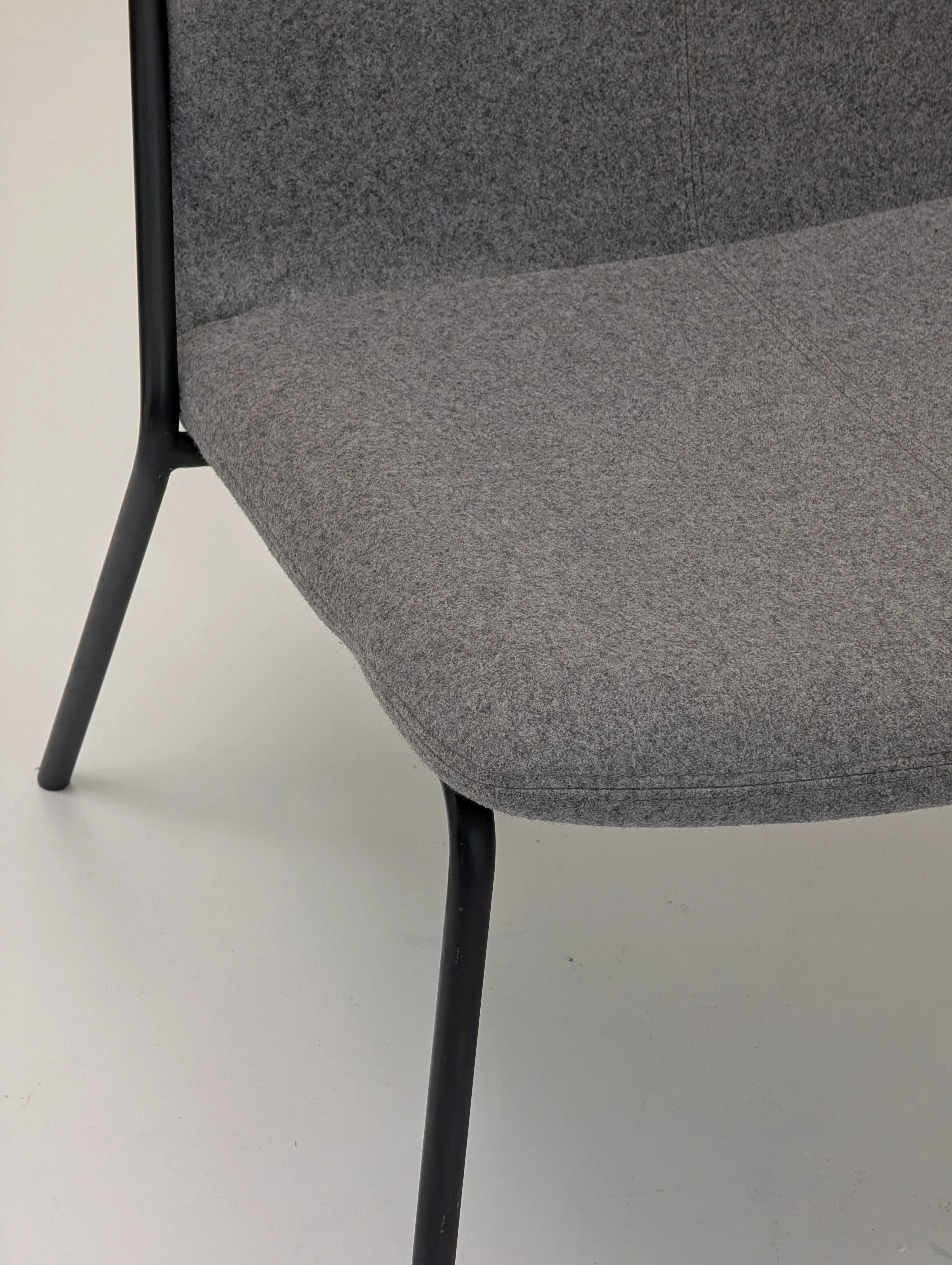 Close-up of modern gray upholstered chair with black metal legs on white floor