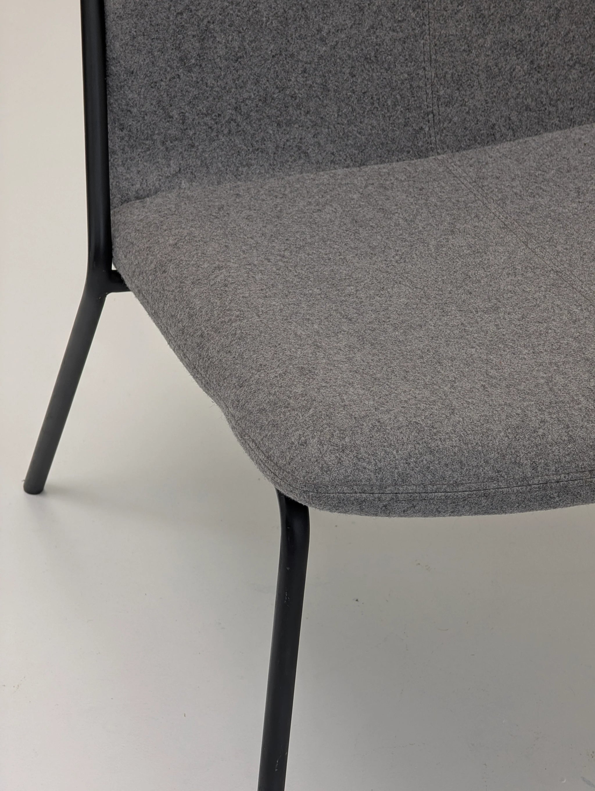 Close-up of modern gray upholstered chair with black metal legs on white floor
