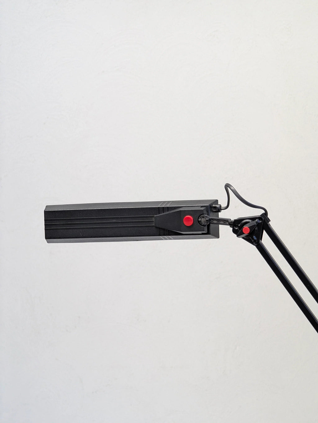 Black adjustable LED desk lamp with red accents against a white wall