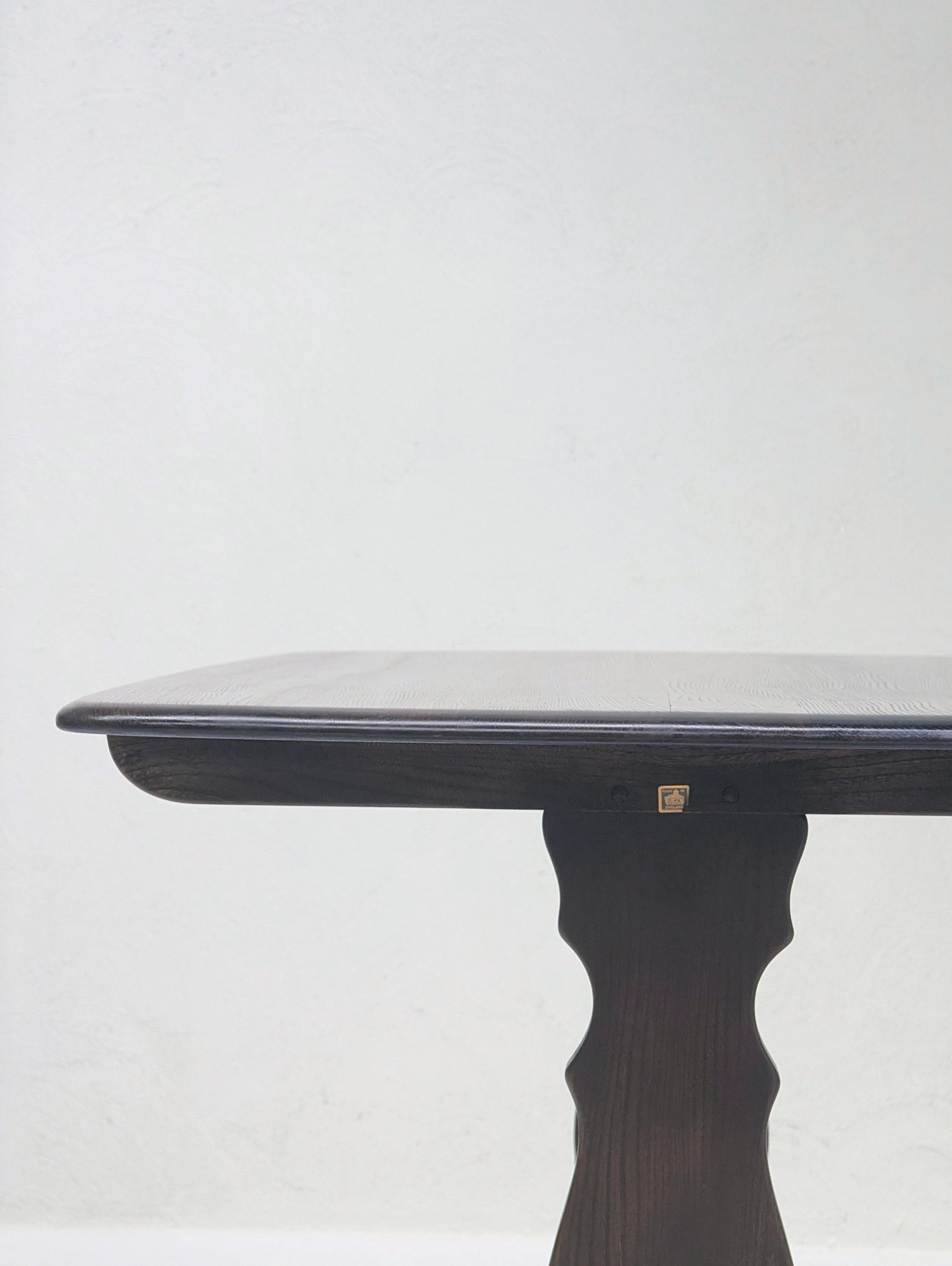 Dark wooden table with curved pedestal leg against plain white wall background