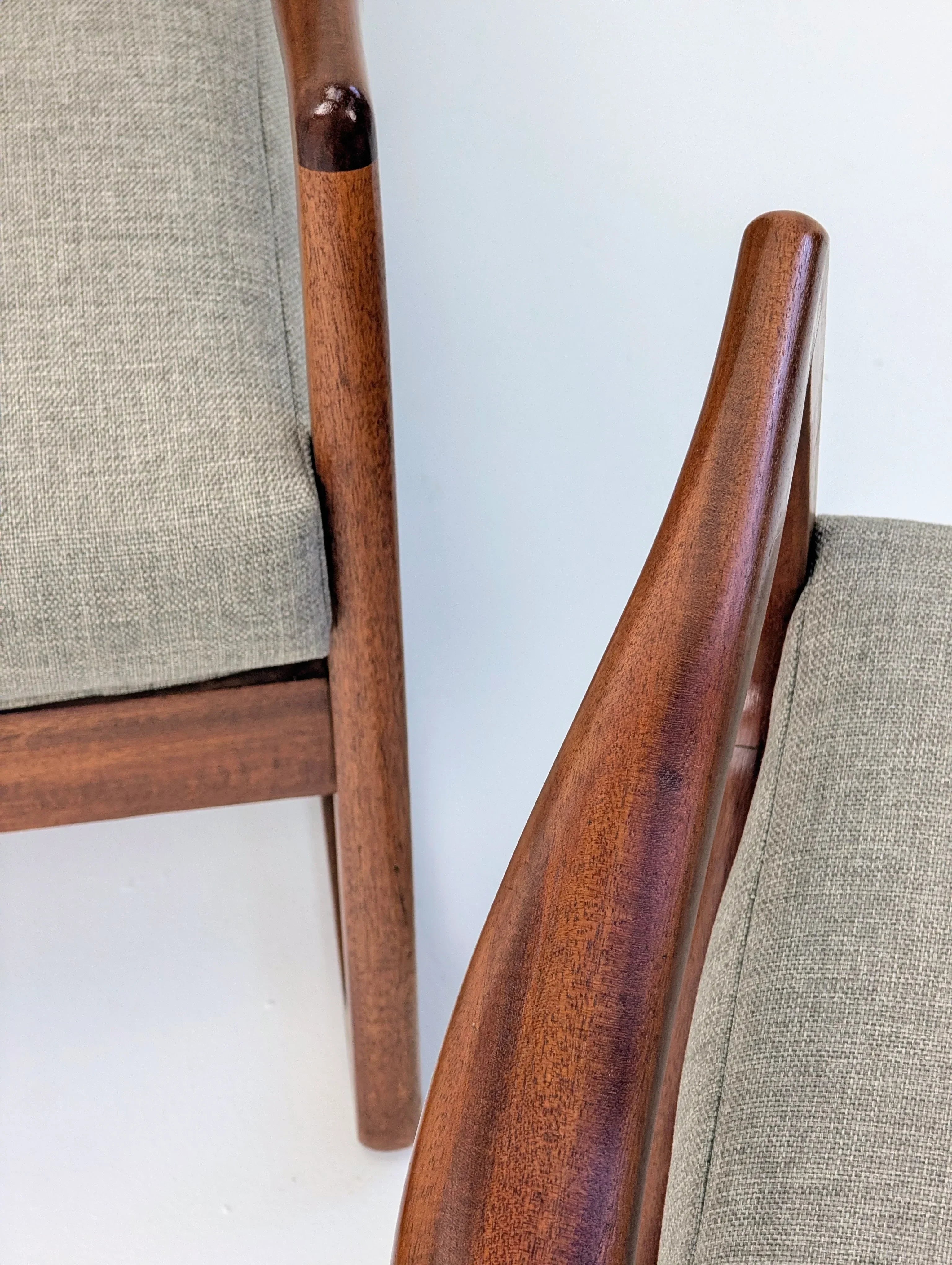 Mid-century modern wooden chairs with gray fabric upholstery on a white background