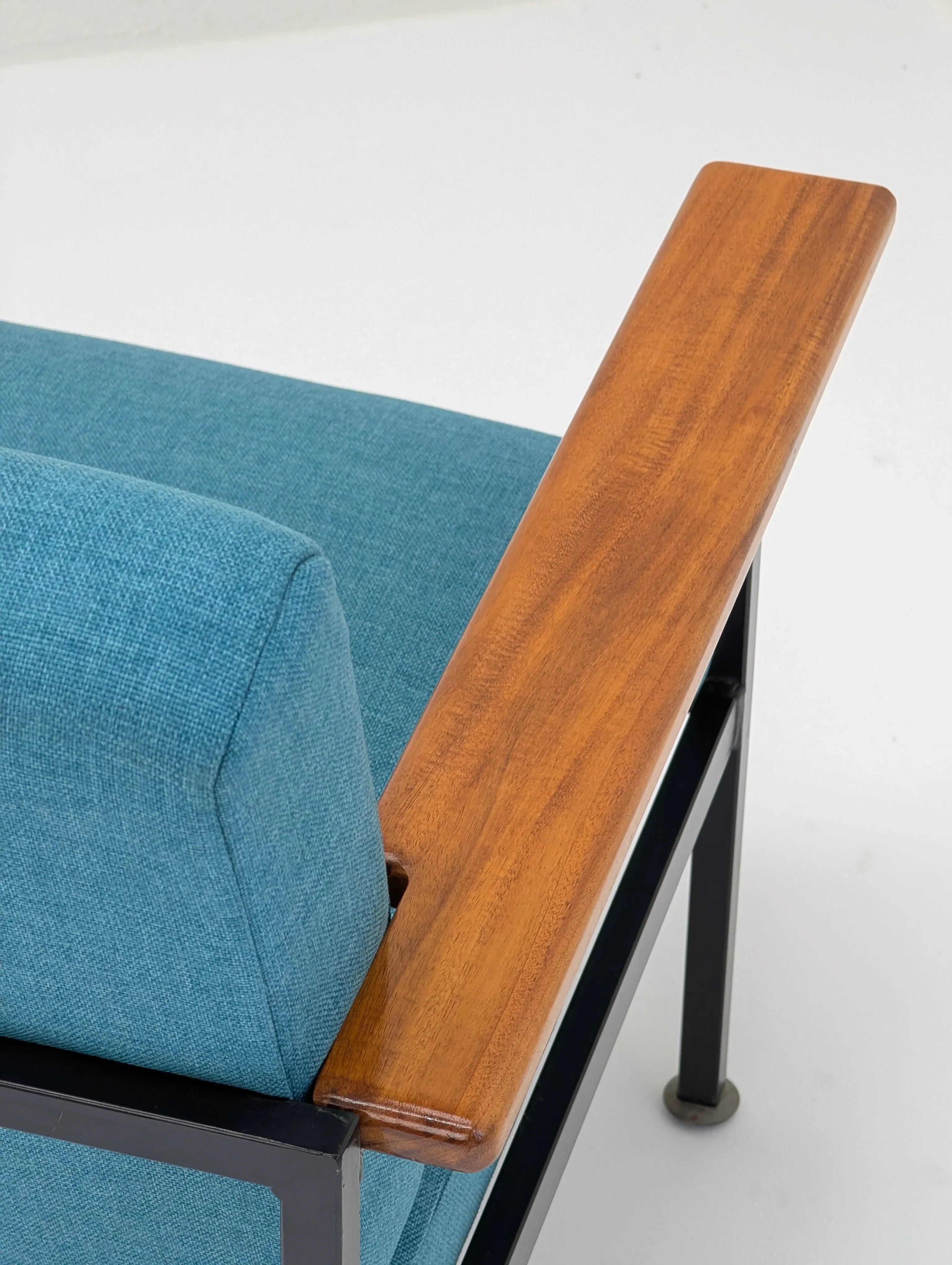 Blue upholstered chair with wooden armrest and black metal frame