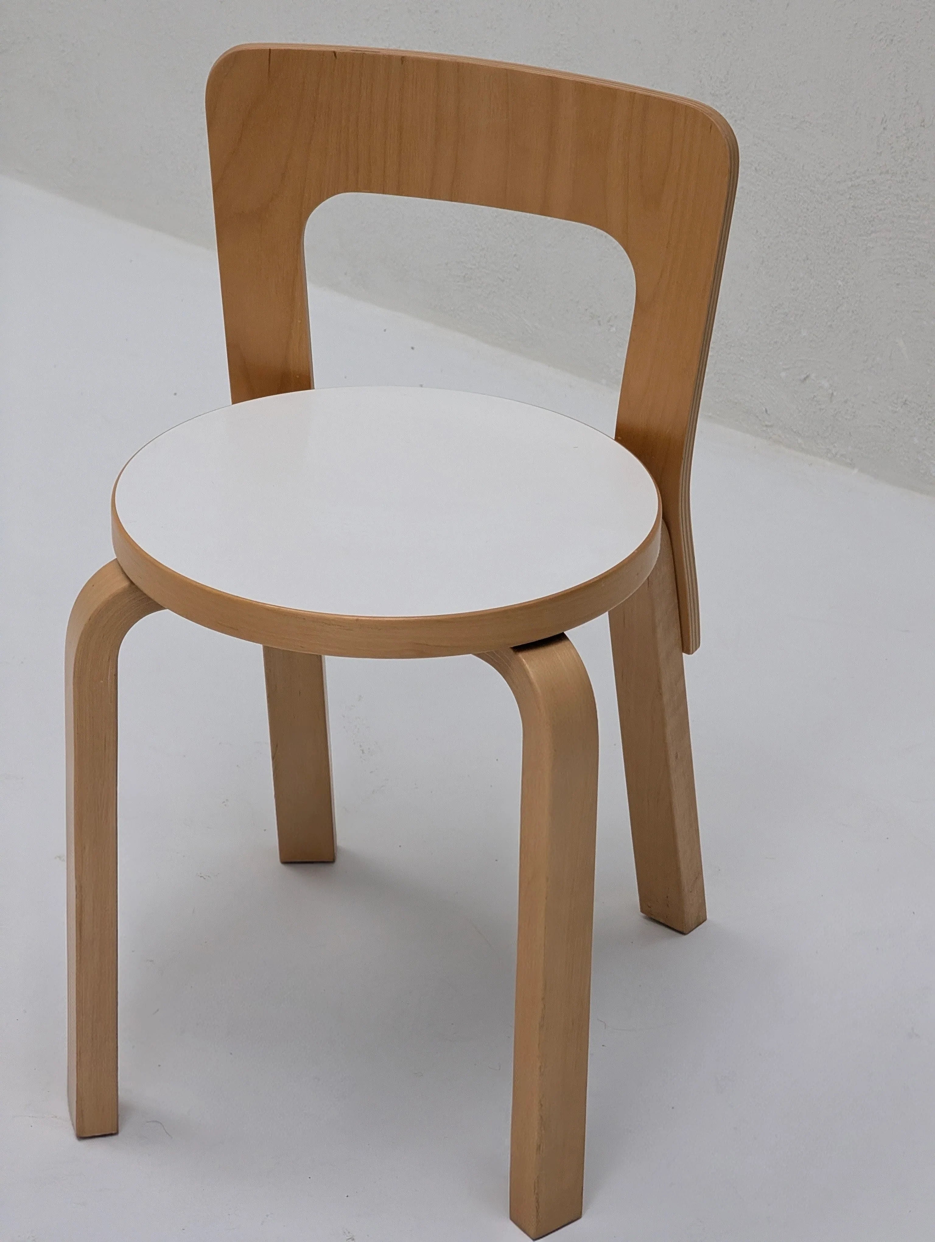 Modern wooden chair with white round seat and natural wood frame on a light background