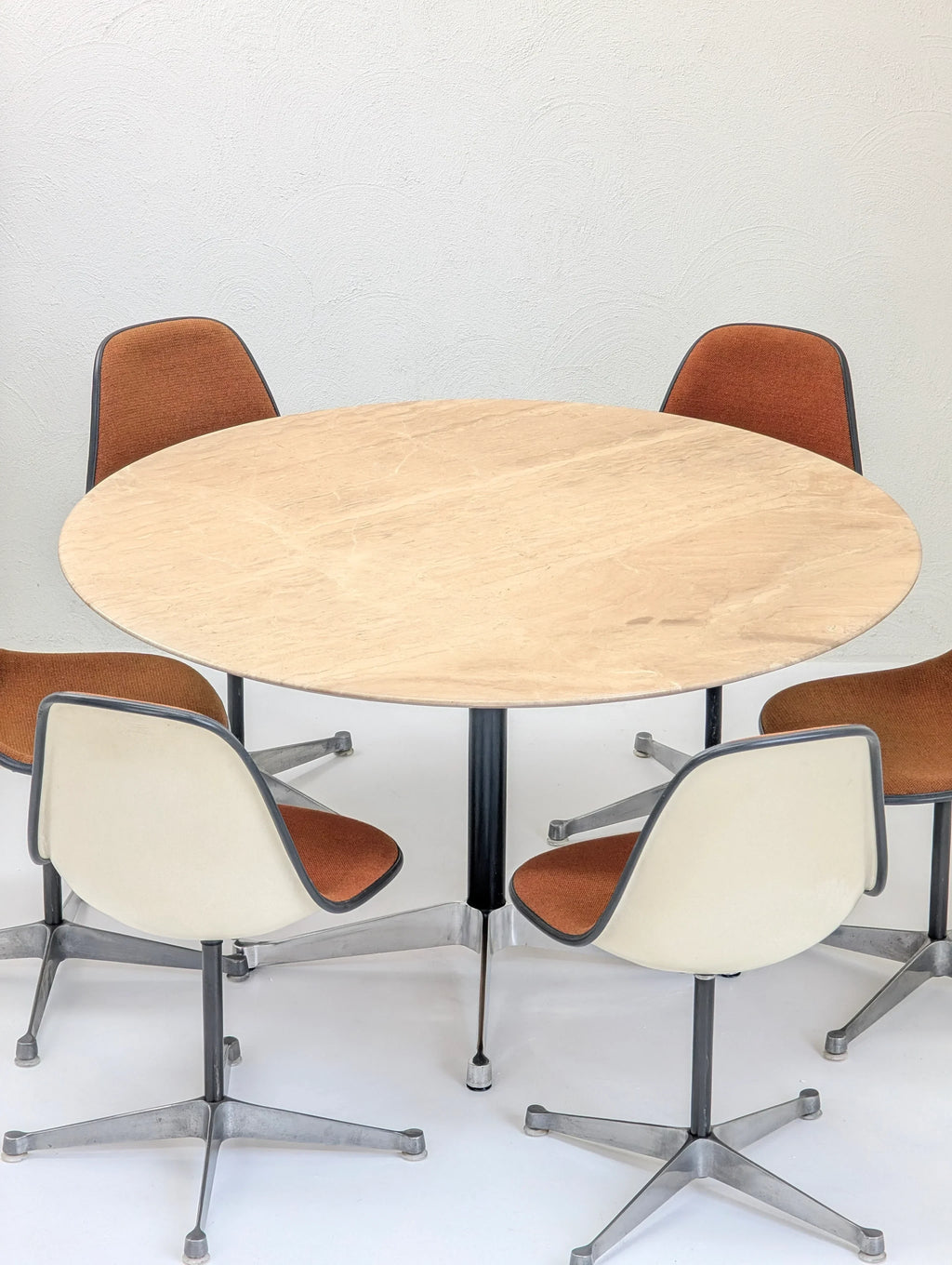 Modern round wooden table with four vintage swivel chairs, brown upholstery, minimalist setting