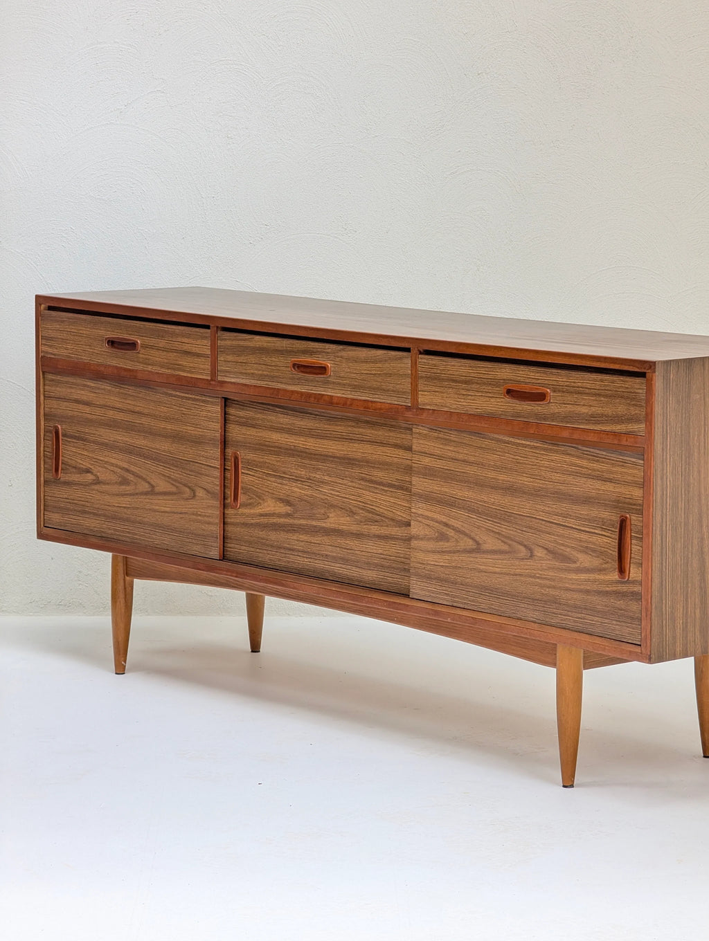 Mid-century modern wooden sideboard with three drawers and sliding doors on tapered legs