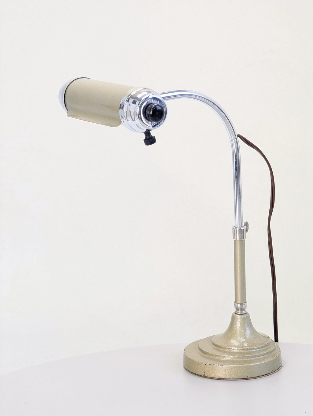 Vintage metal desk lamp with chrome arm and beige shade on white table