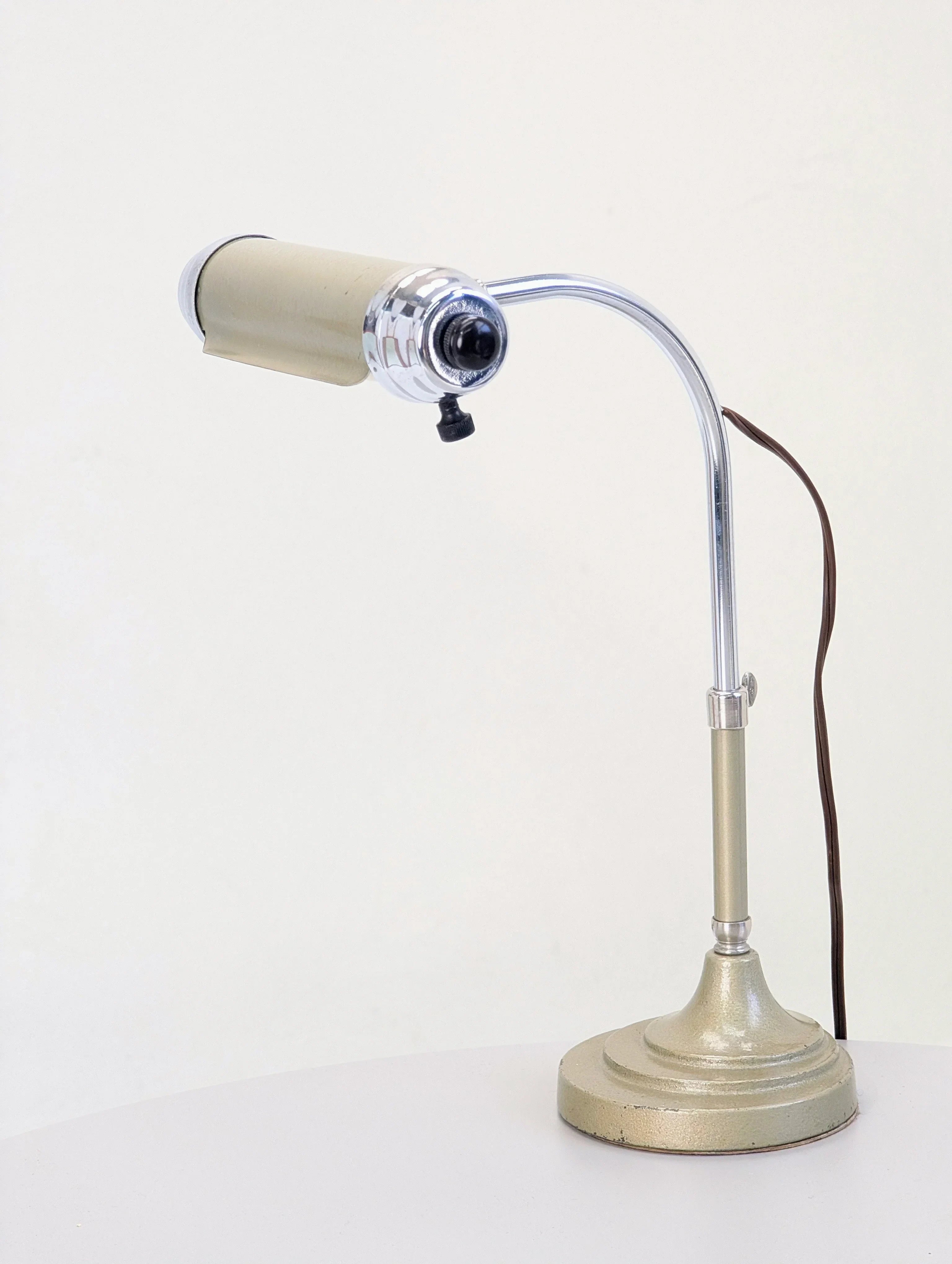 Vintage metal desk lamp with chrome arm and beige shade on white table