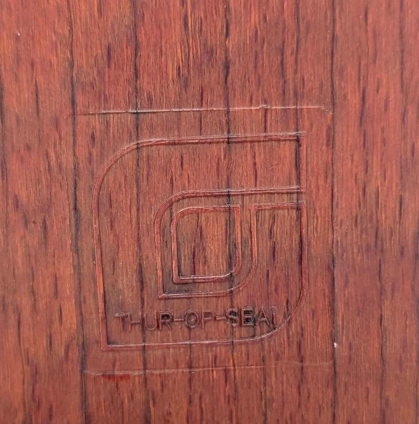 Embossed THUR-OP-SEAL logo on reddish-brown wood grain surface