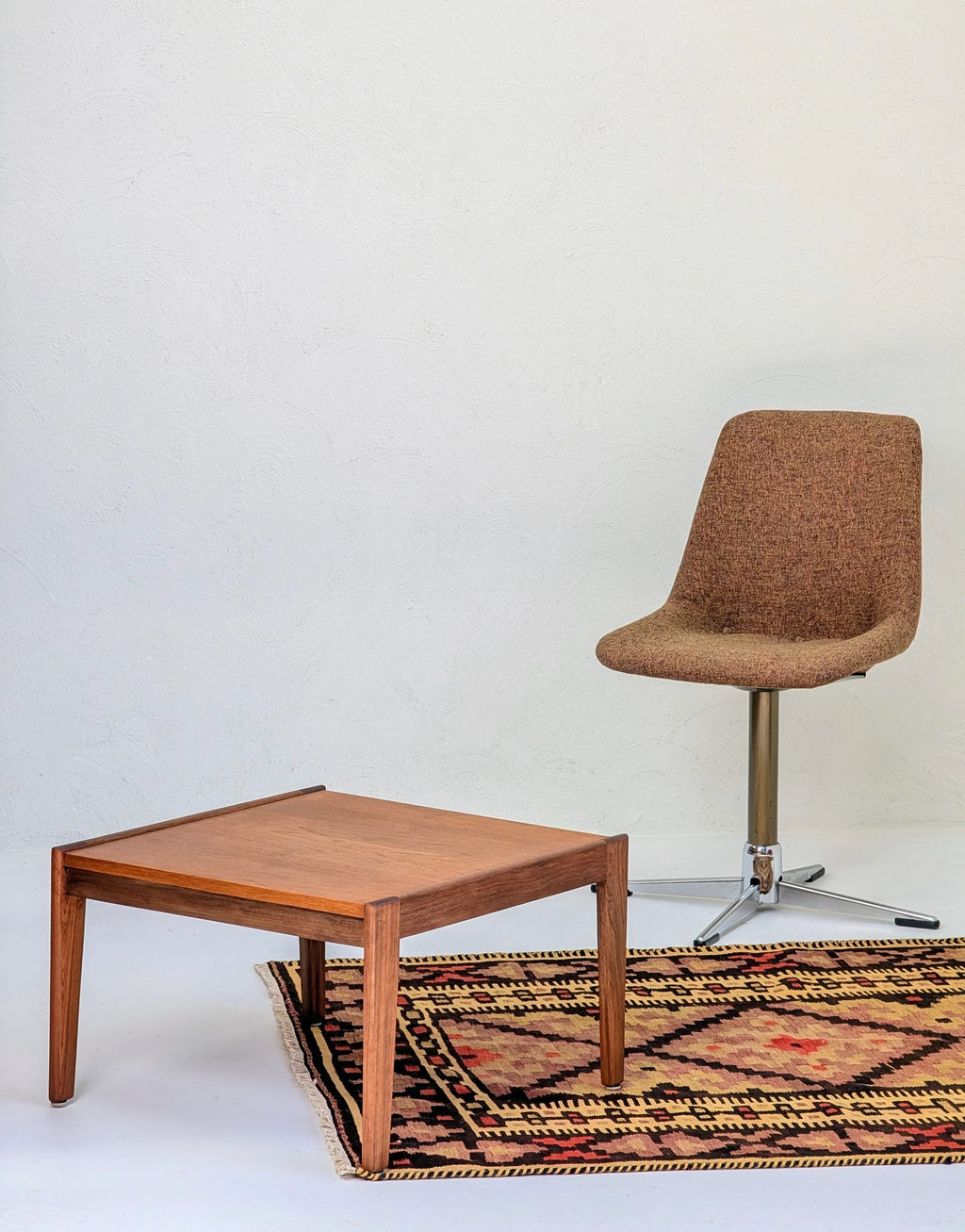 Mid-century modern brown fabric swivel chair and wooden coffee table on patterned rug