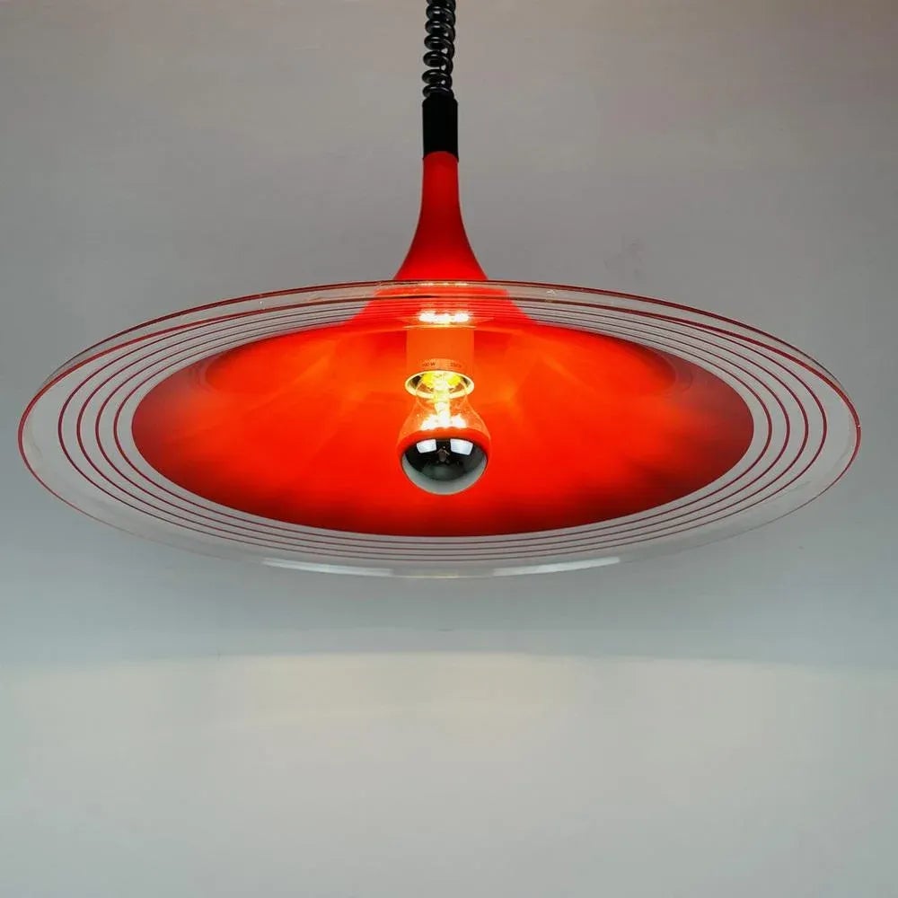 Mid-century modern red and clear circular pendant light with exposed bulb and coiled black cord