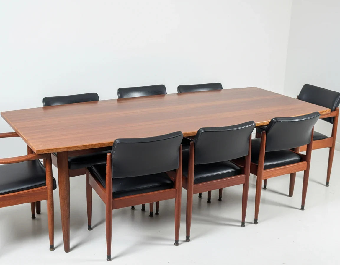 Mid-century modern wooden dining table with eight black leather and teak chairs in minimalist setting