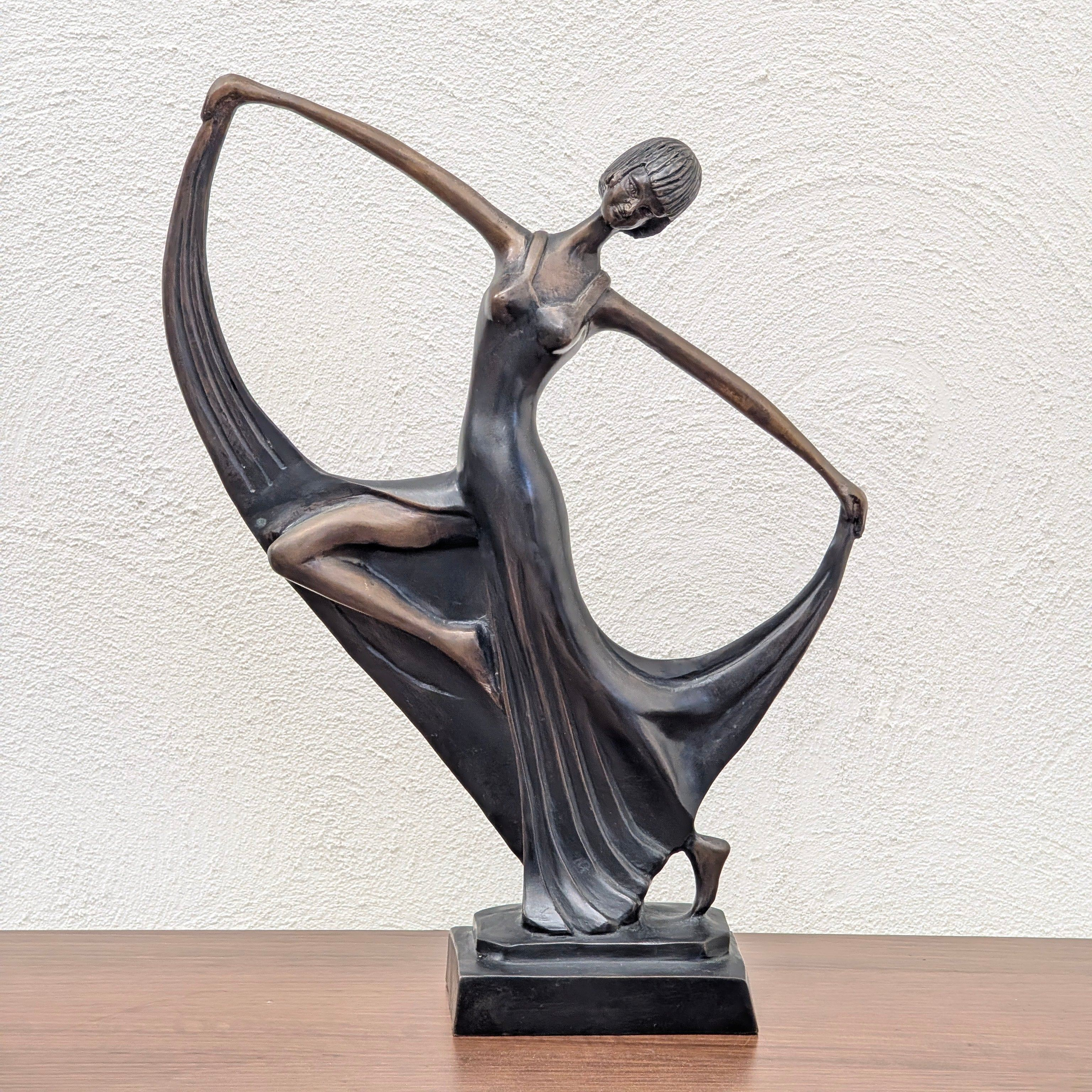 Mid-century modern bronze sculpture of a dancing woman with flowing dress on wooden surface