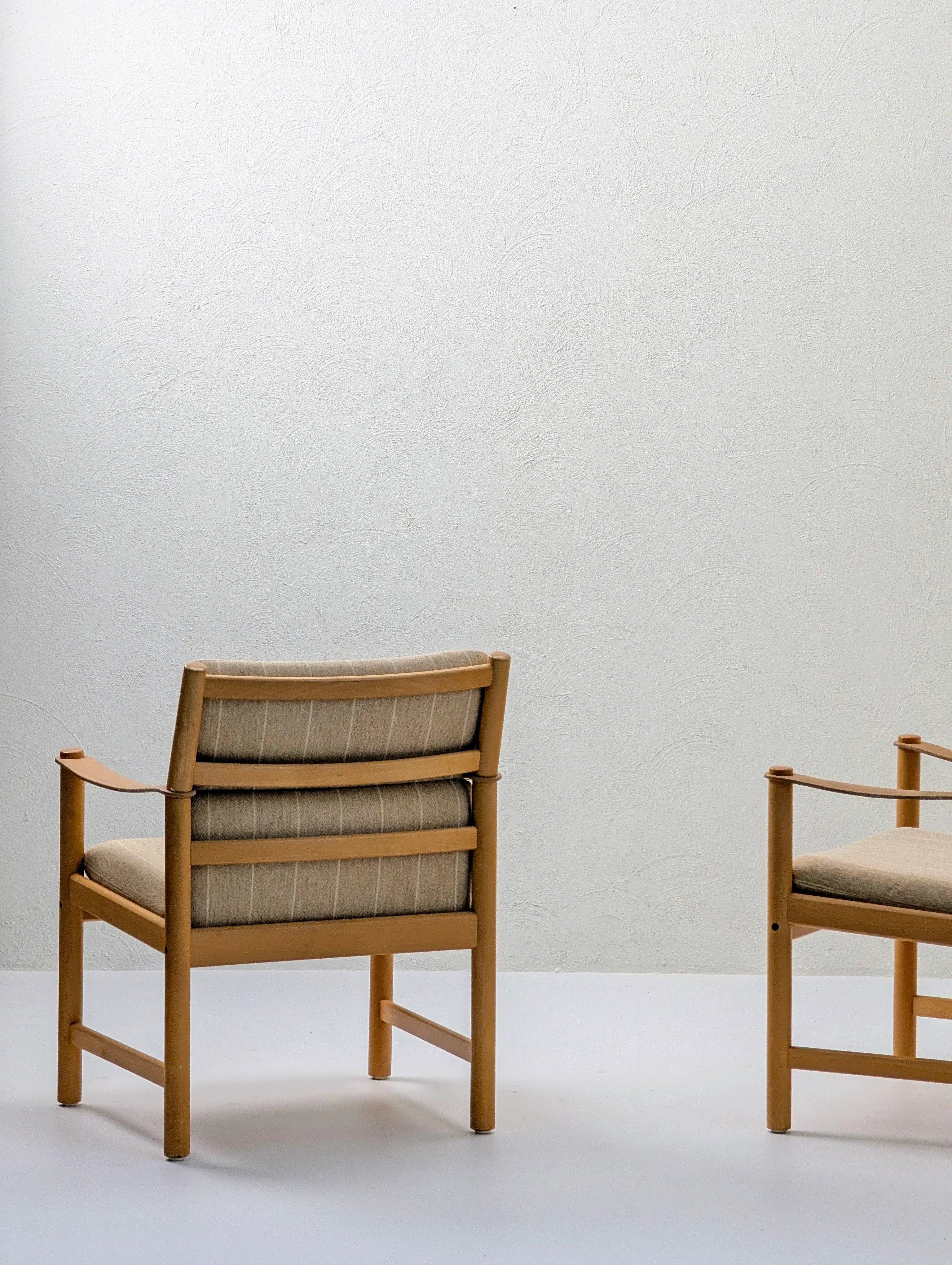 Minimalist modern wood chairs with beige cushions against a textured white wall