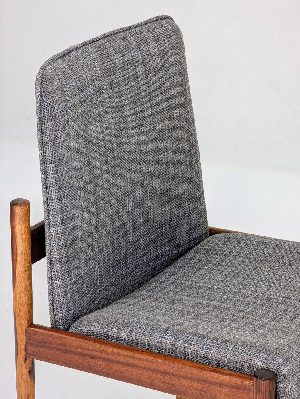 Modern chair with gray textured fabric upholstery and wooden frame against white background