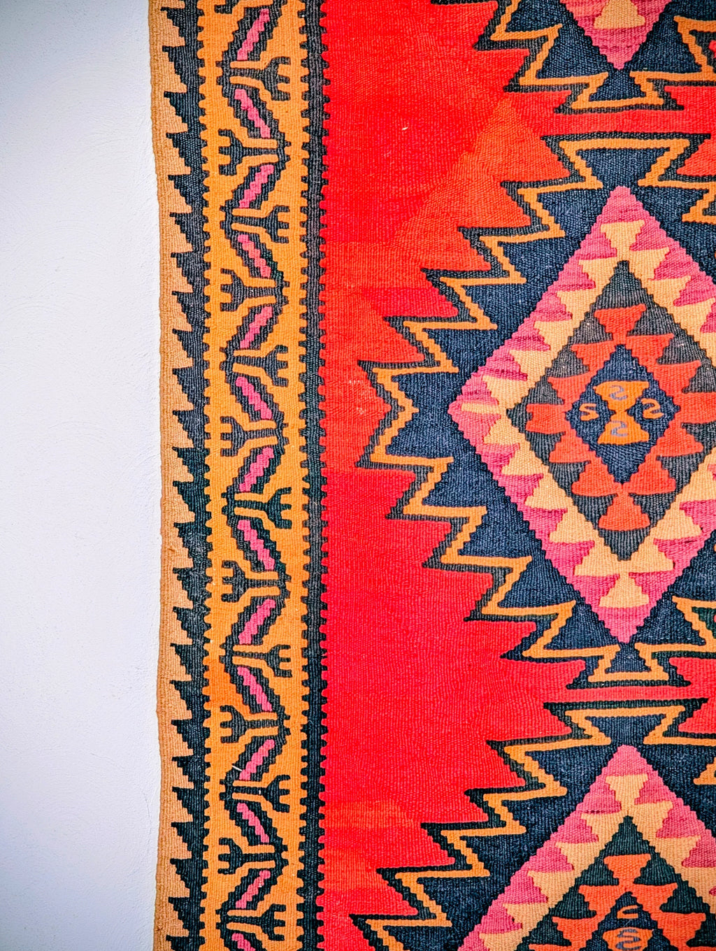 Colorful geometric pattern on traditional red kilim rug with zigzag and diamond designs