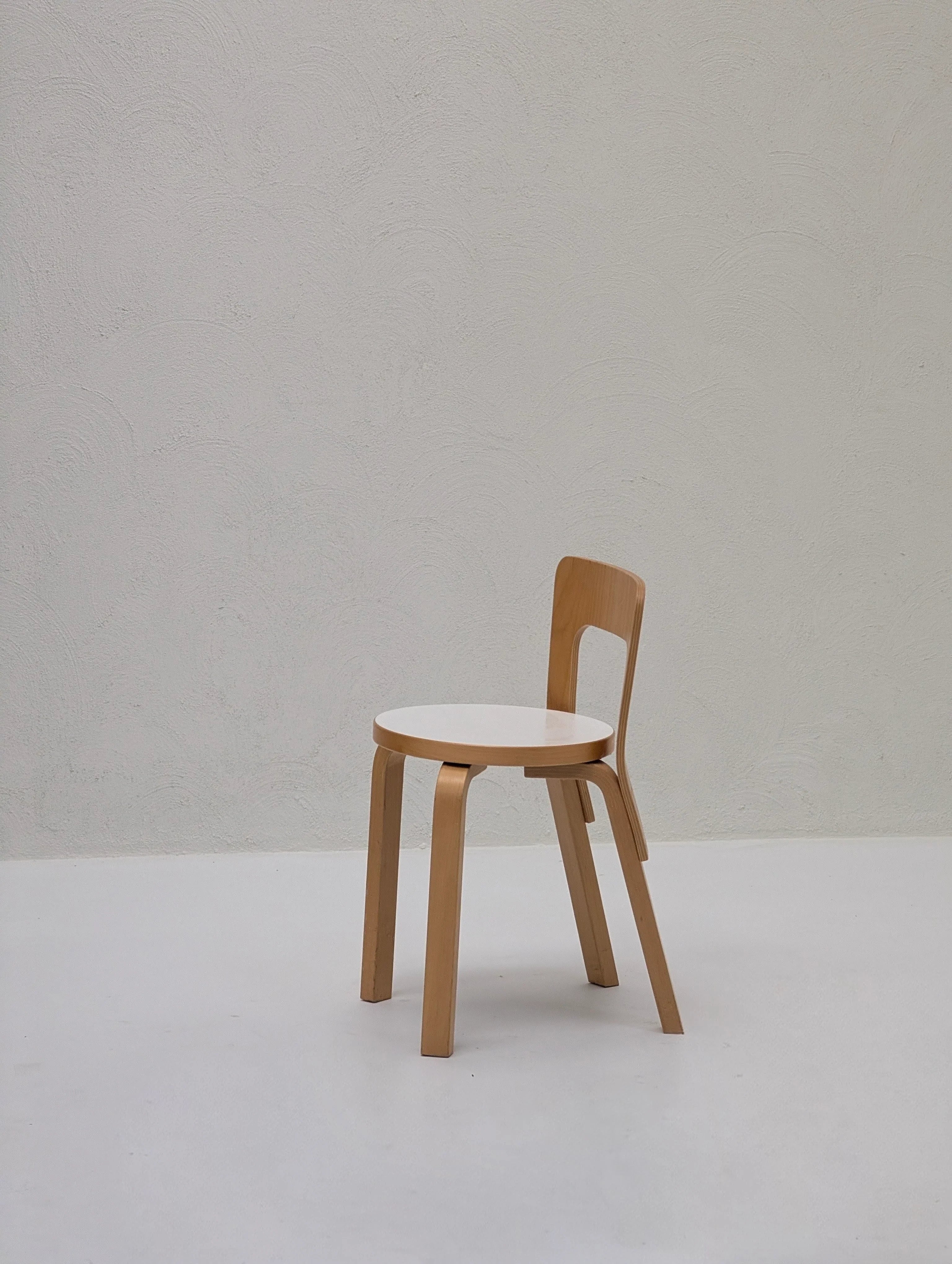 Minimalist wooden chair with white seat in a bright, modern room with textured wall