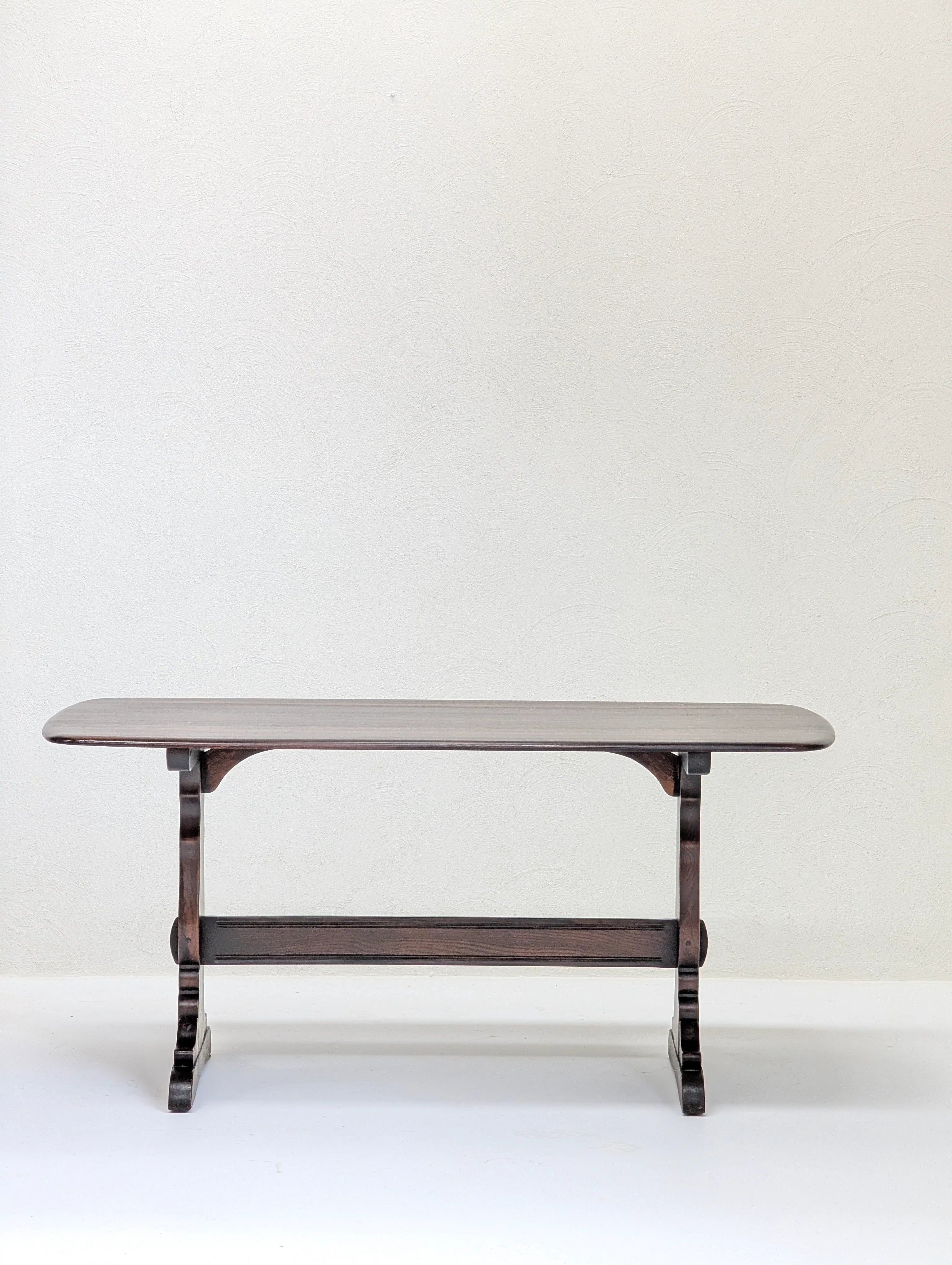 Minimalist dark wood bench with curved legs against a textured white wall