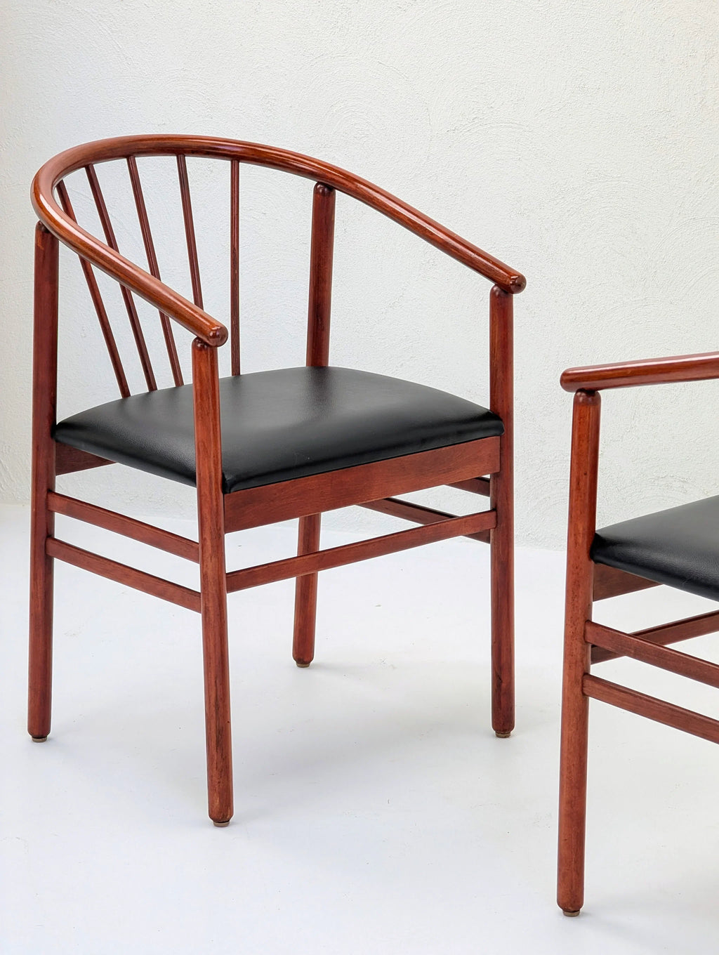 Mid-century modern wooden chair with black cushion and curved backrest in minimal setting