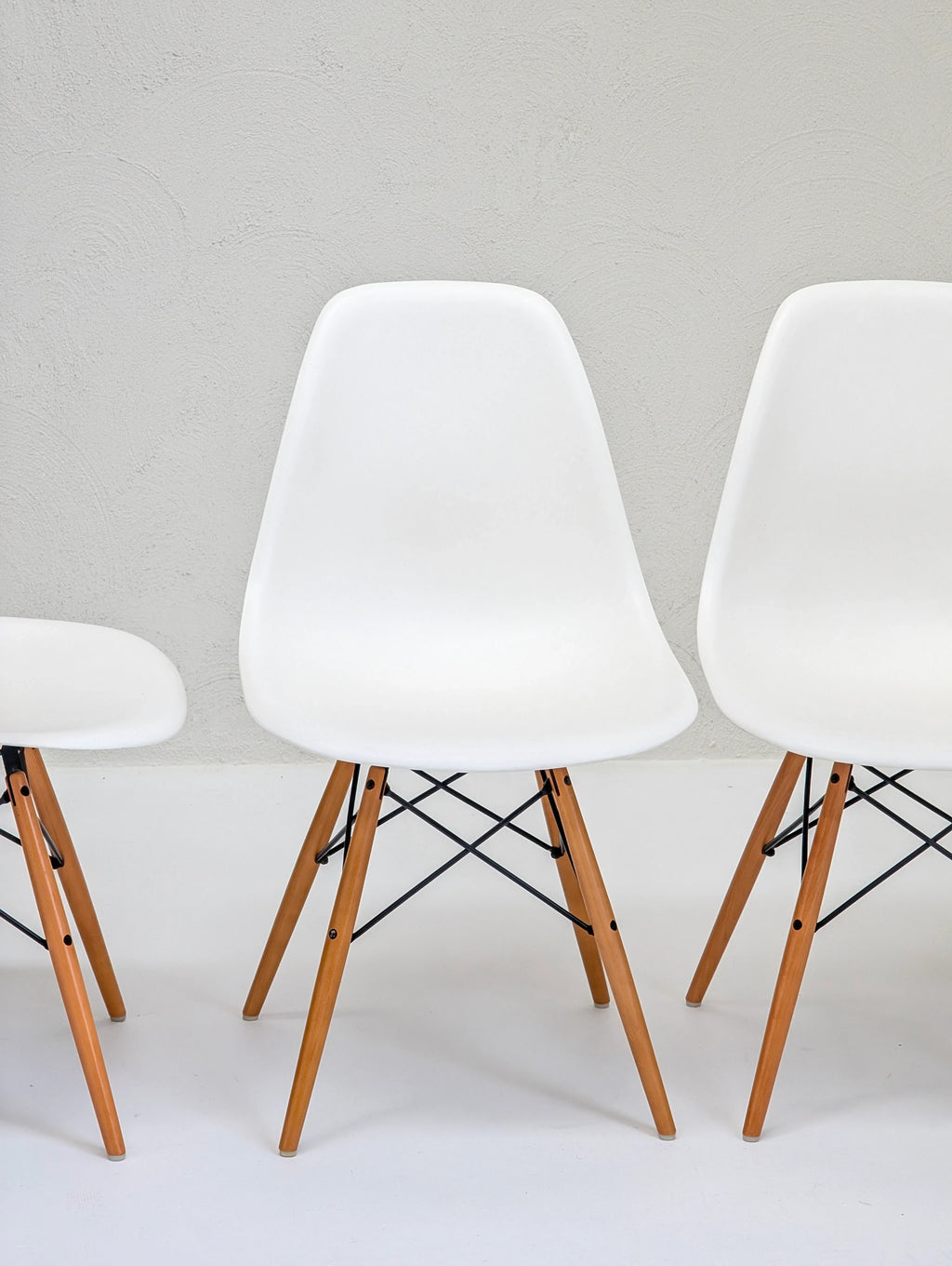 Modern white chairs with wooden legs against a light gray wall, minimalist furniture