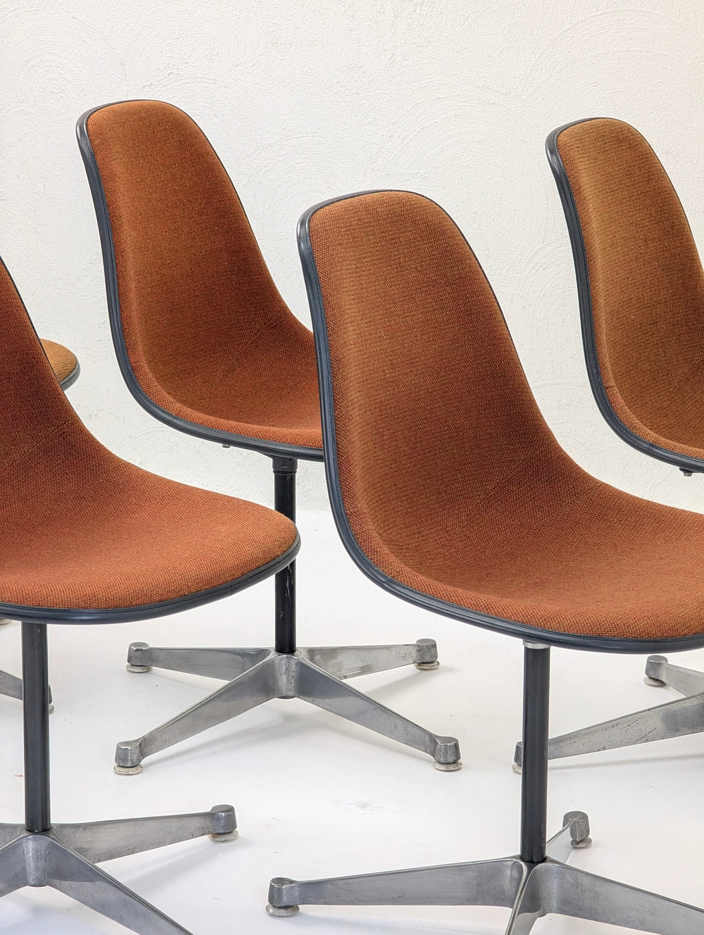 Set of vintage mid-century modern brown fabric swivel chairs with metal bases on white floor