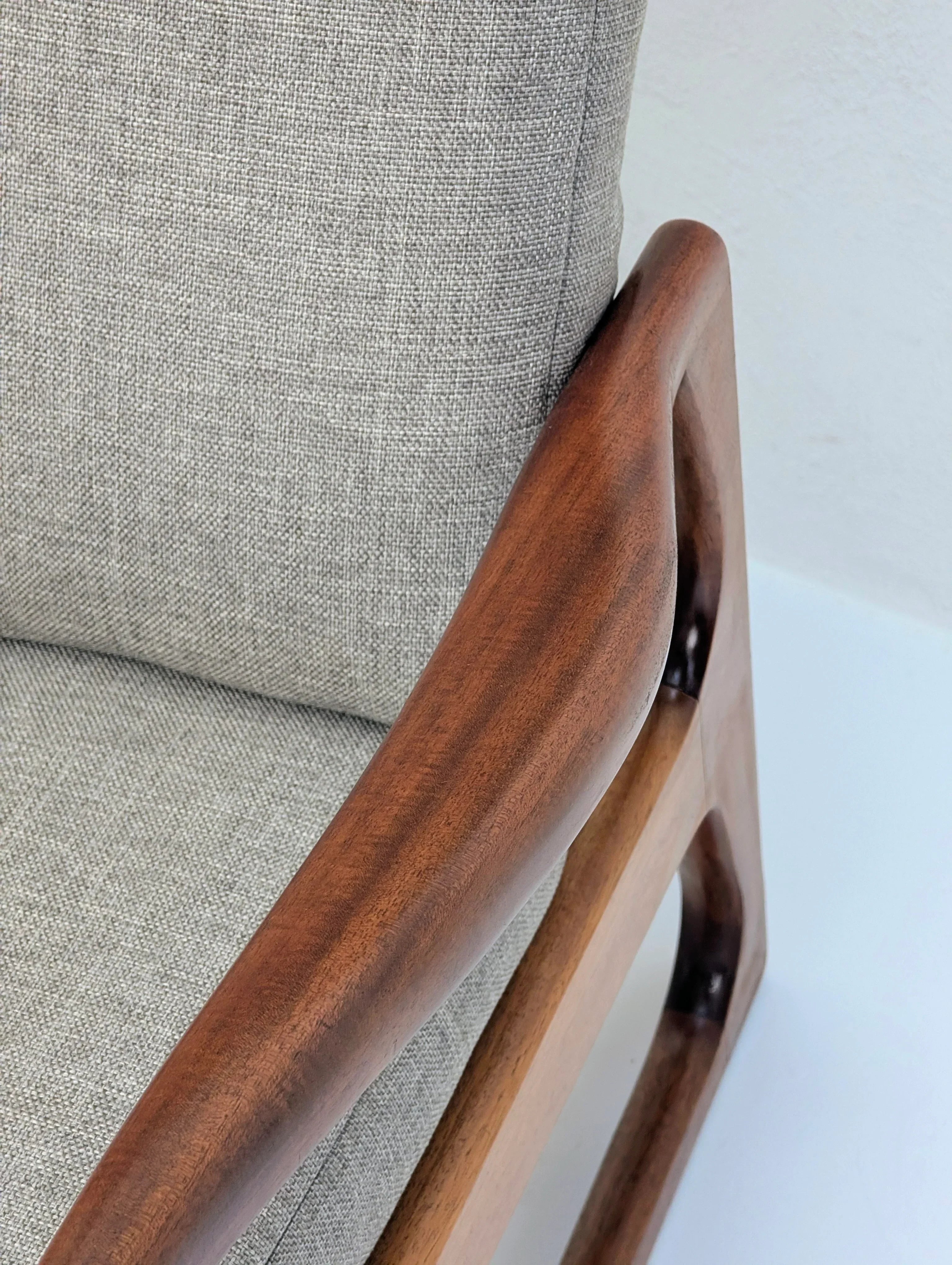 Modern armchair with light gray fabric and smooth wooden armrest, minimalistic design