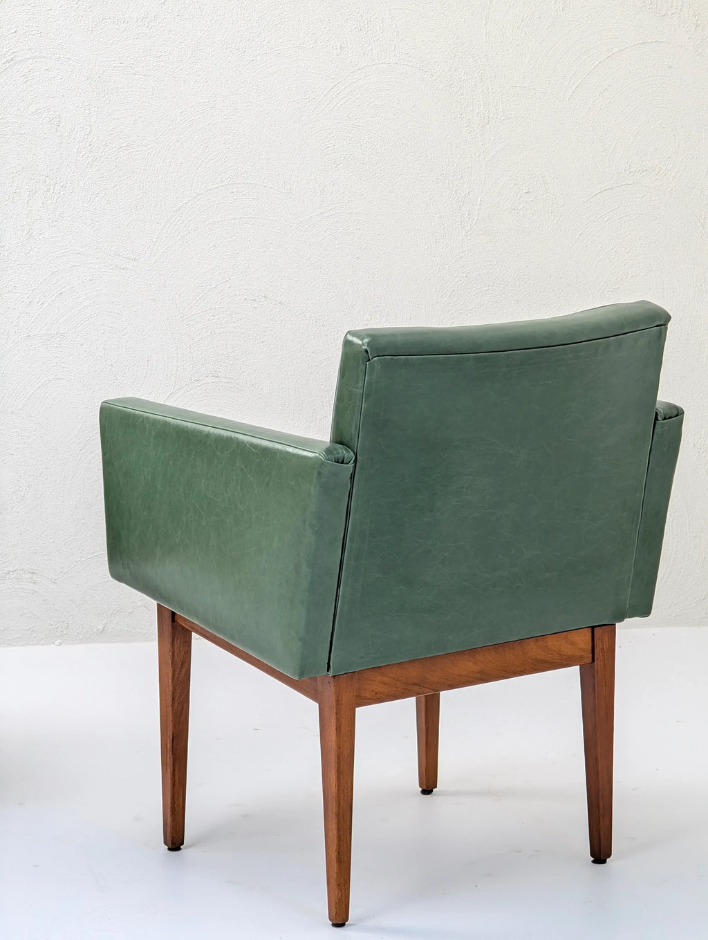 Mid-century modern green leather armchair with wooden legs on white background