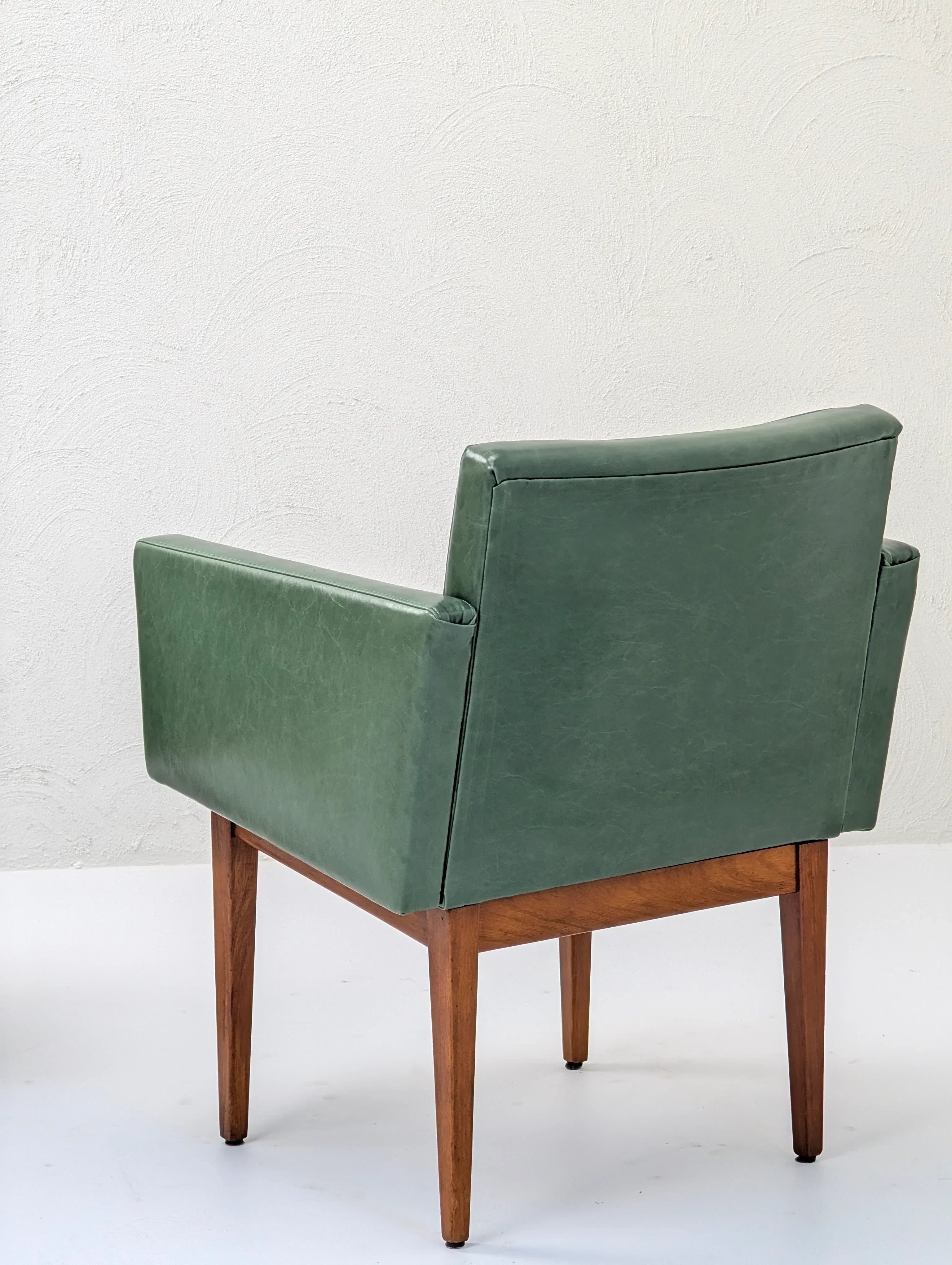 Mid-century modern green leather armchair with wooden legs on white background