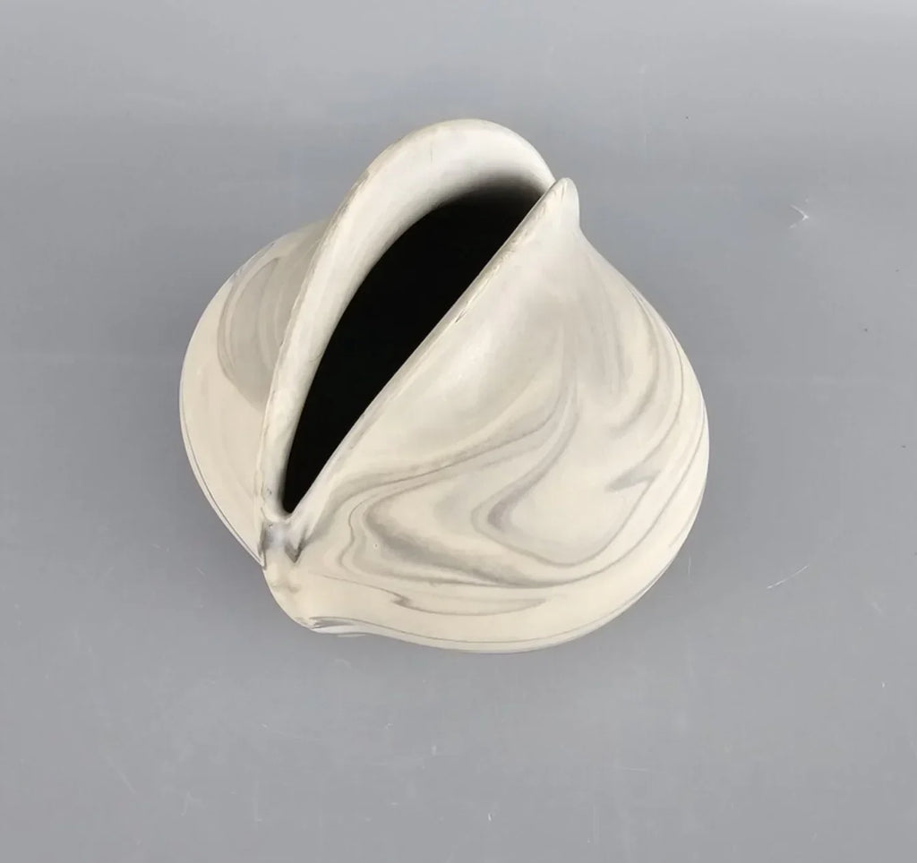 Marbled ceramic vase with organic curved shape on gray background