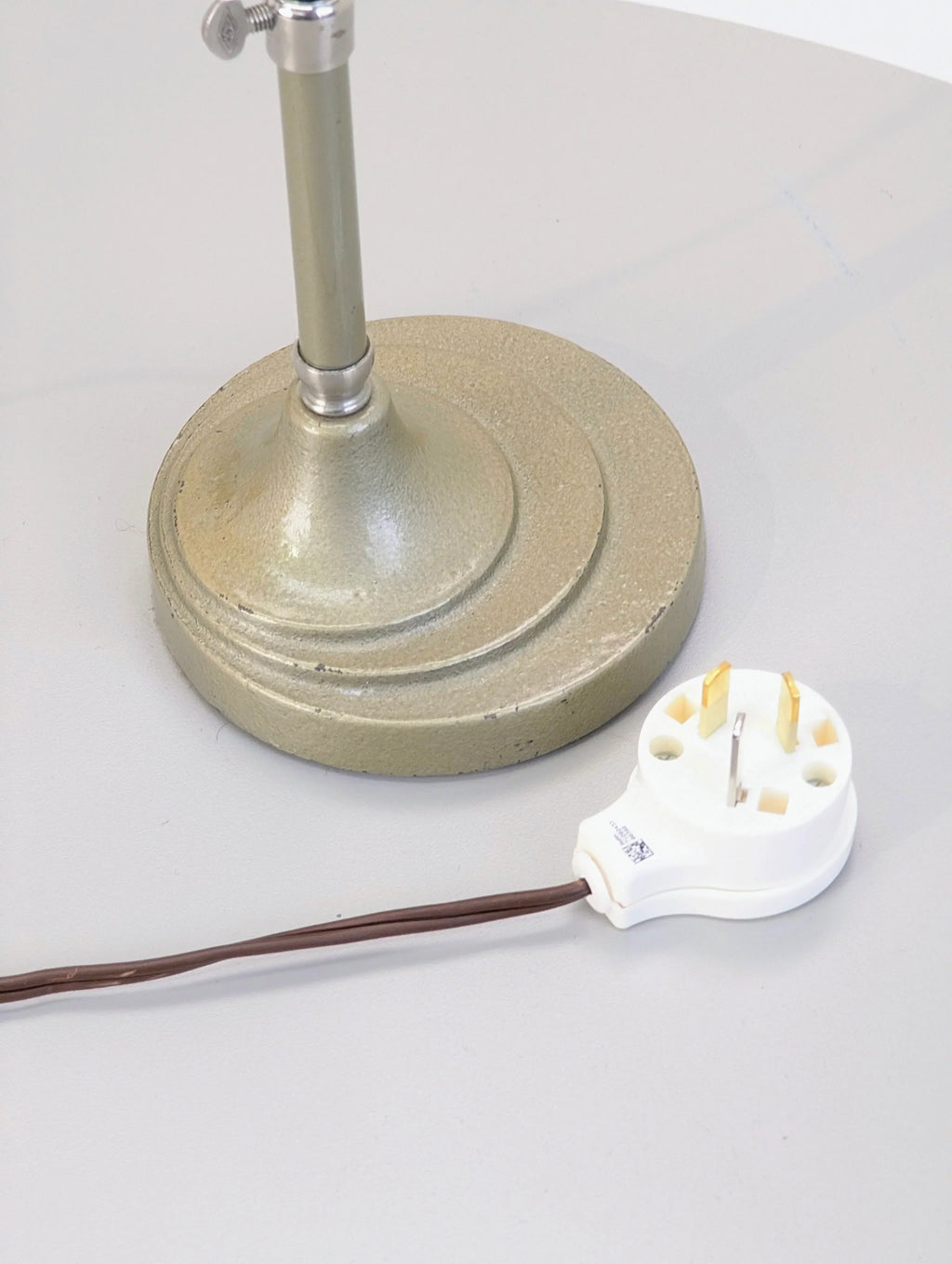 Close-up of vintage lamp base with UK three-pin plug on grey table