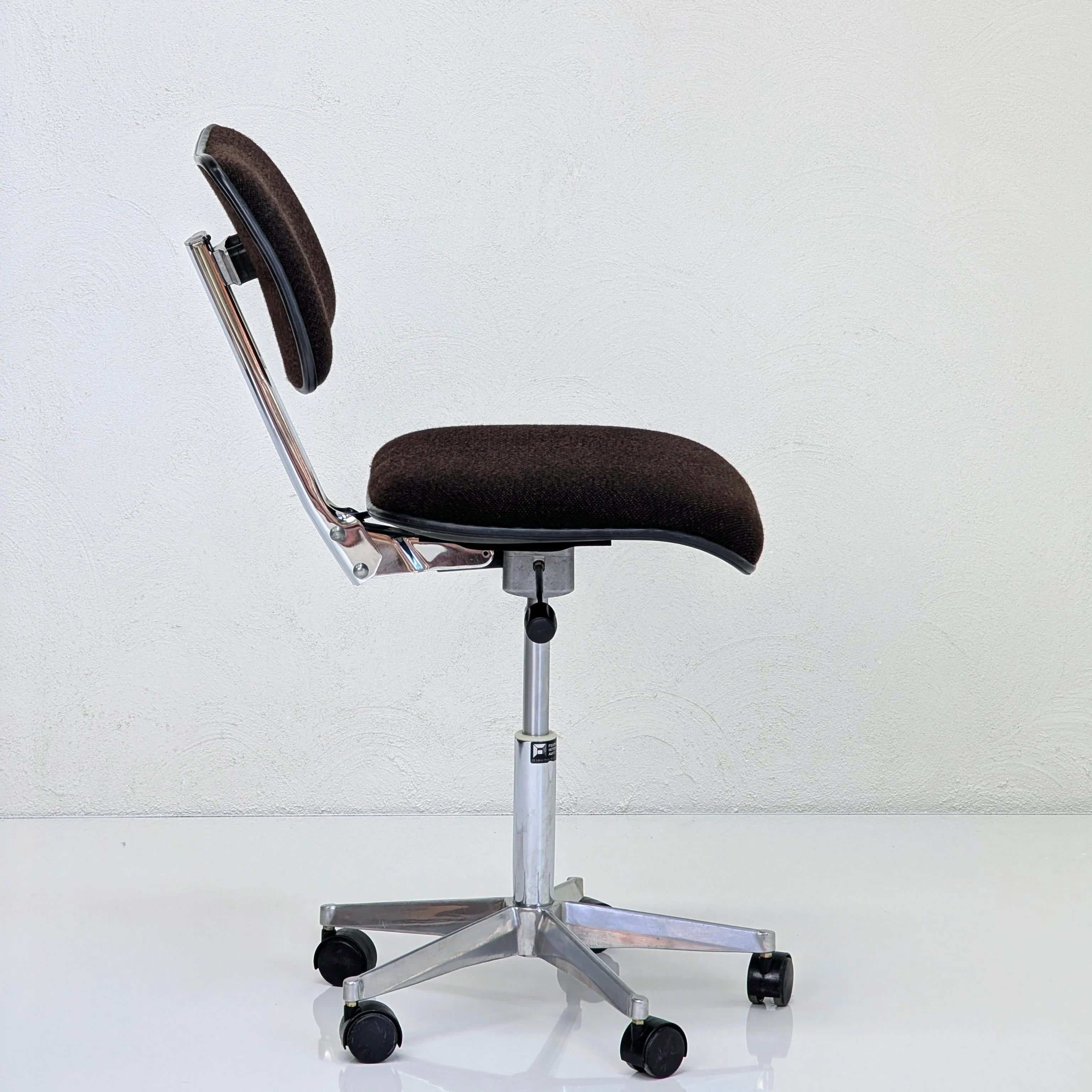 Modern brown office chair with chrome base and wheels against white wall