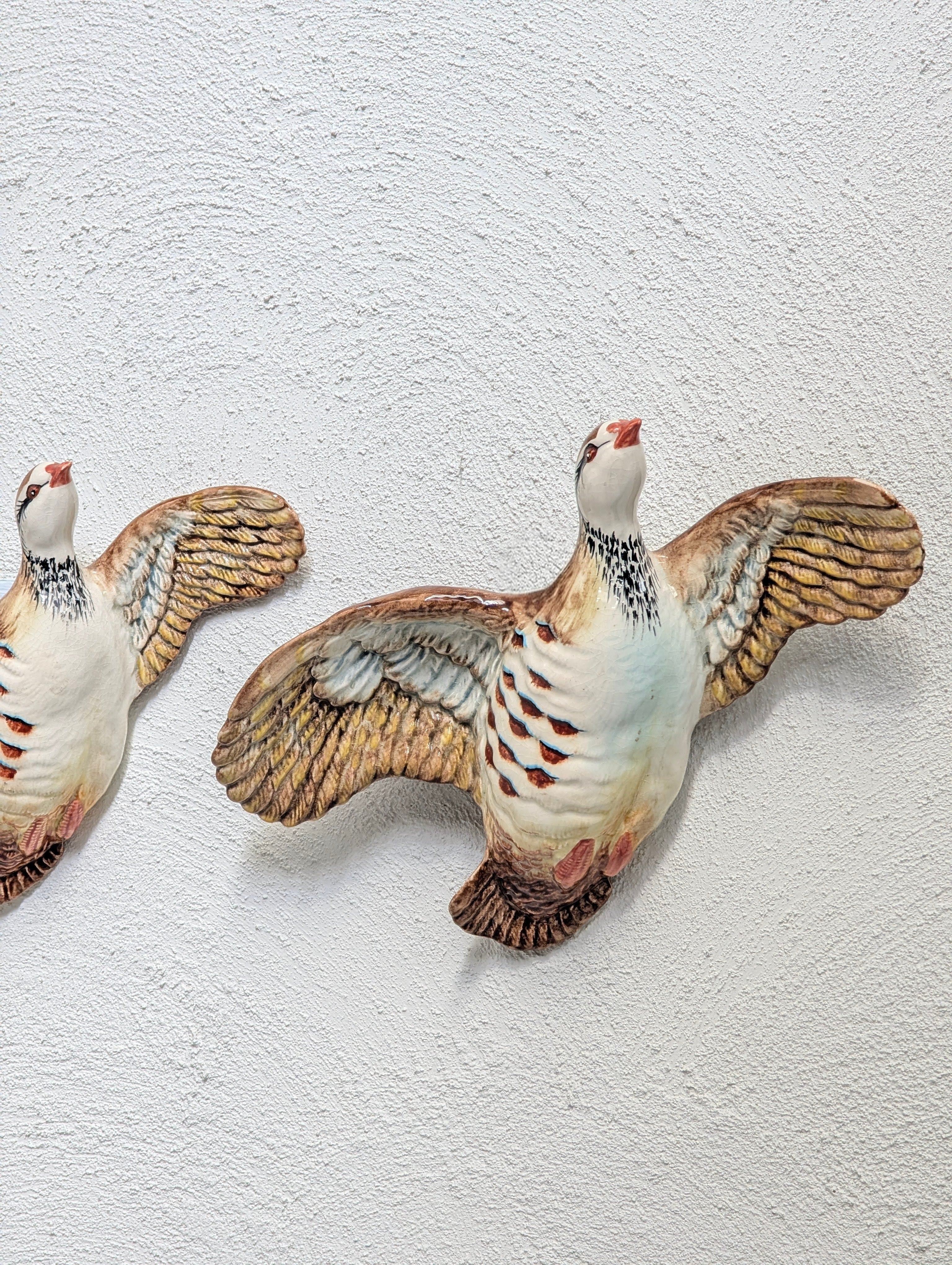Ceramic wall decor of two flying birds with outstretched wings on textured white wall