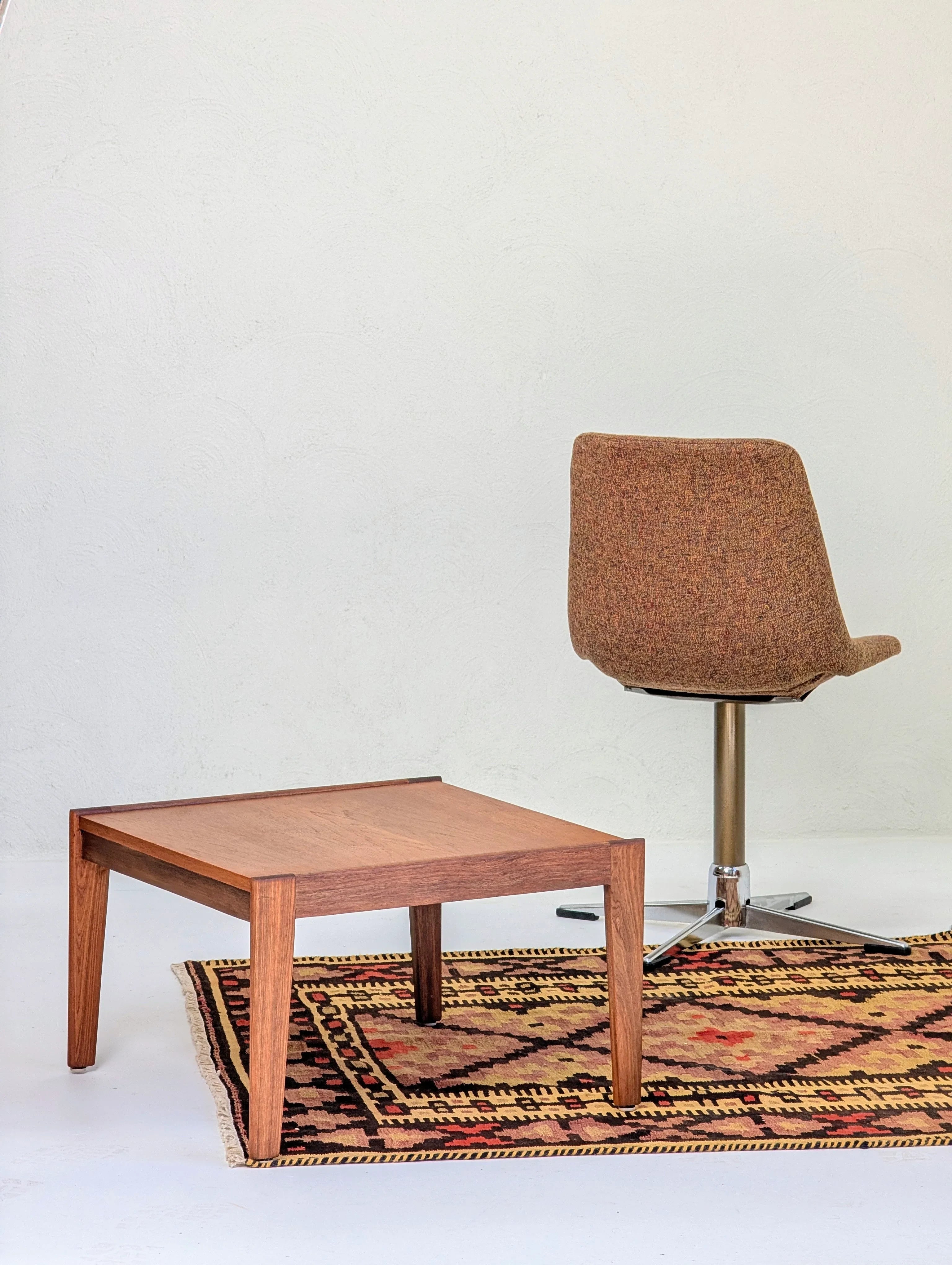 Wooden coffee table and brown swivel chair on patterned rug in minimalist room