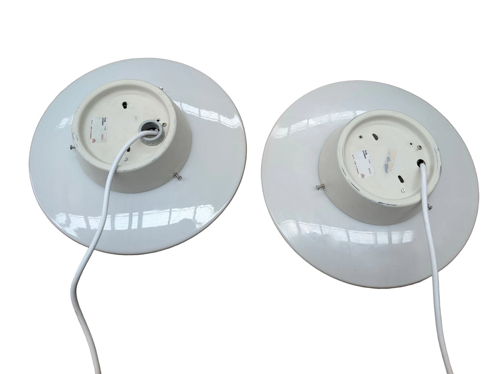 Pair of white industrial round pendant light fixtures with cables on a white background