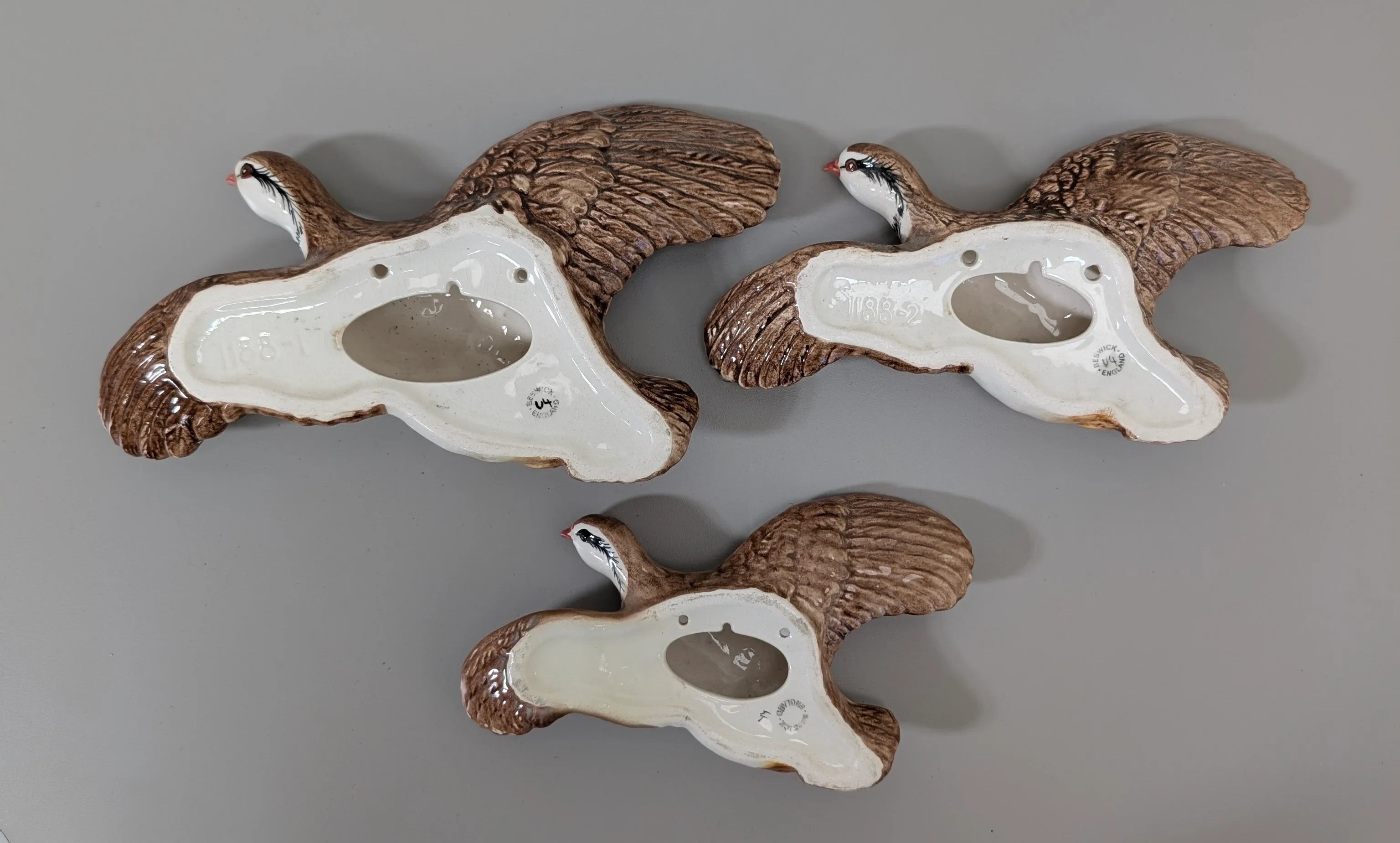 Ceramic flying bird figurines, glazed on one side and brown with detailed feathers on the other