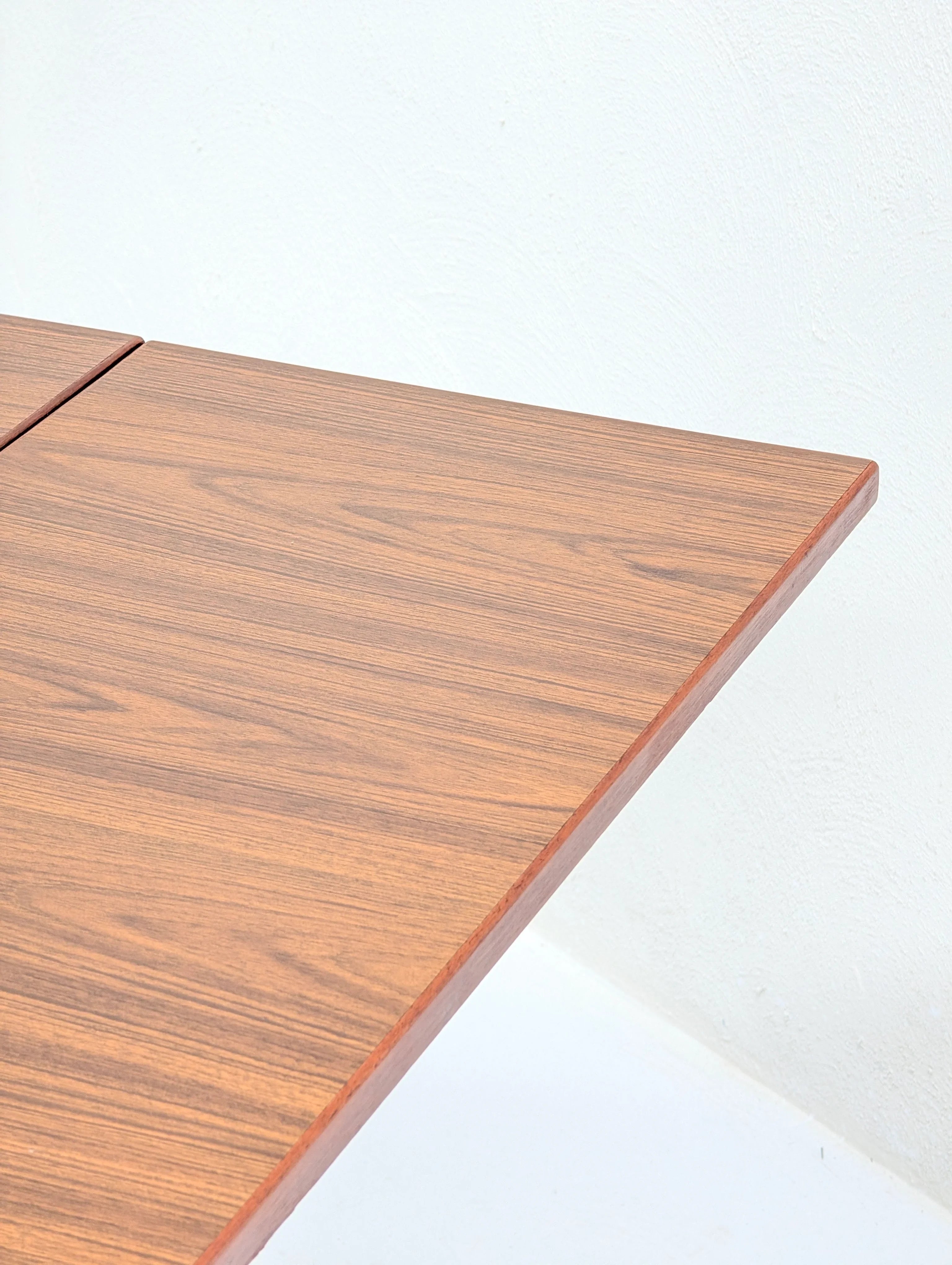 Close-up of wooden table corner with smooth wood grain against white textured wall