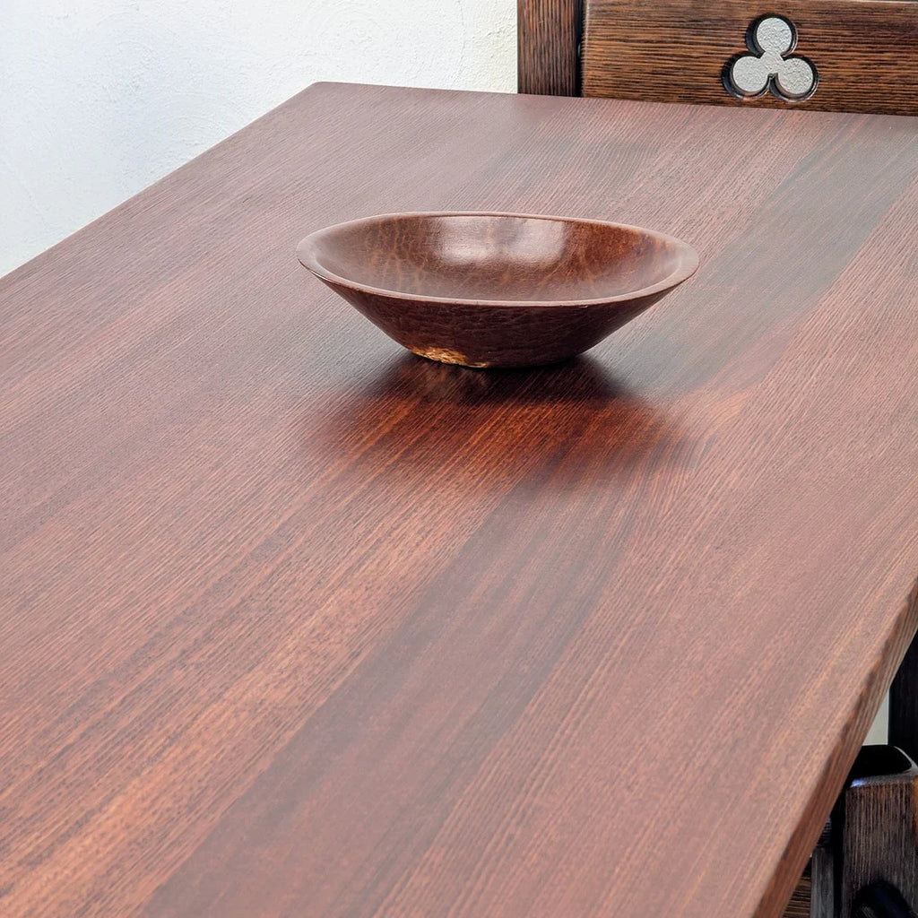 Brown wooden bowl on polished dark wood table with carved wooden chair back