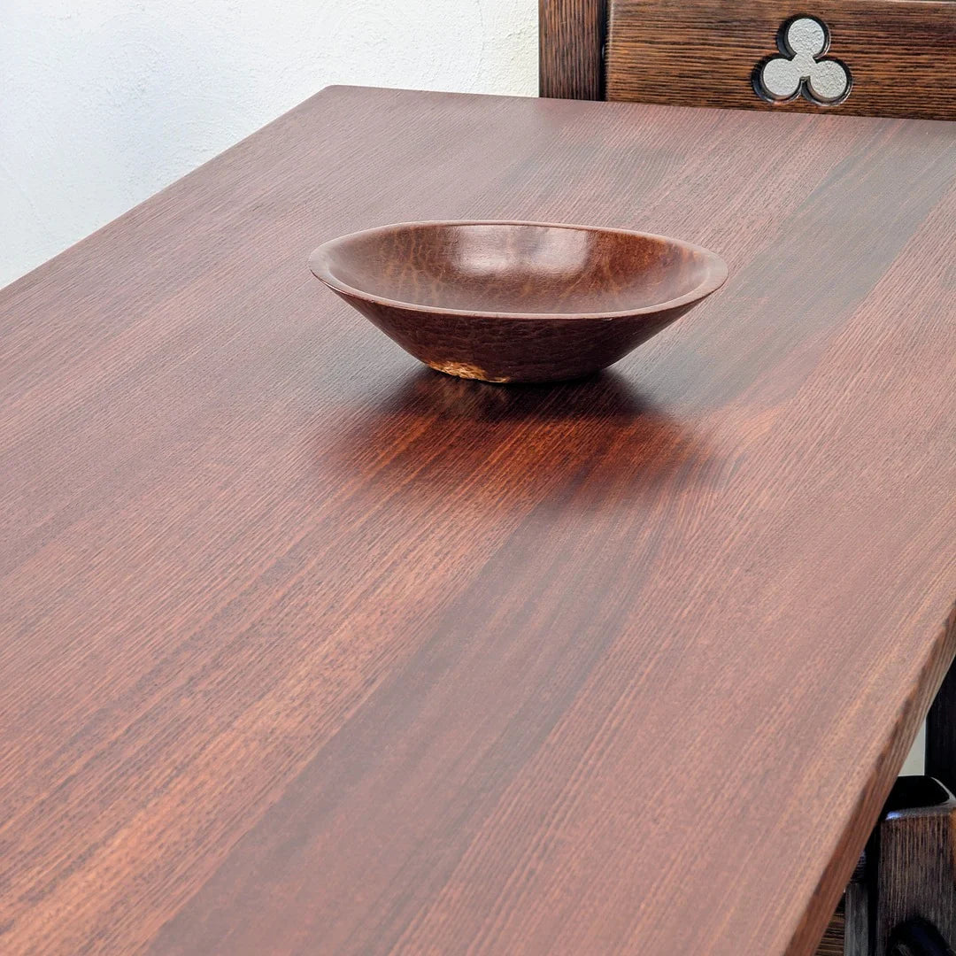 Brown wooden bowl on polished dark wood table with carved wooden chair back