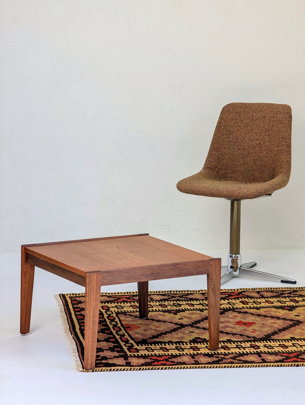 Mid-century modern brown upholstered swivel chair next to wooden coffee table on patterned rug