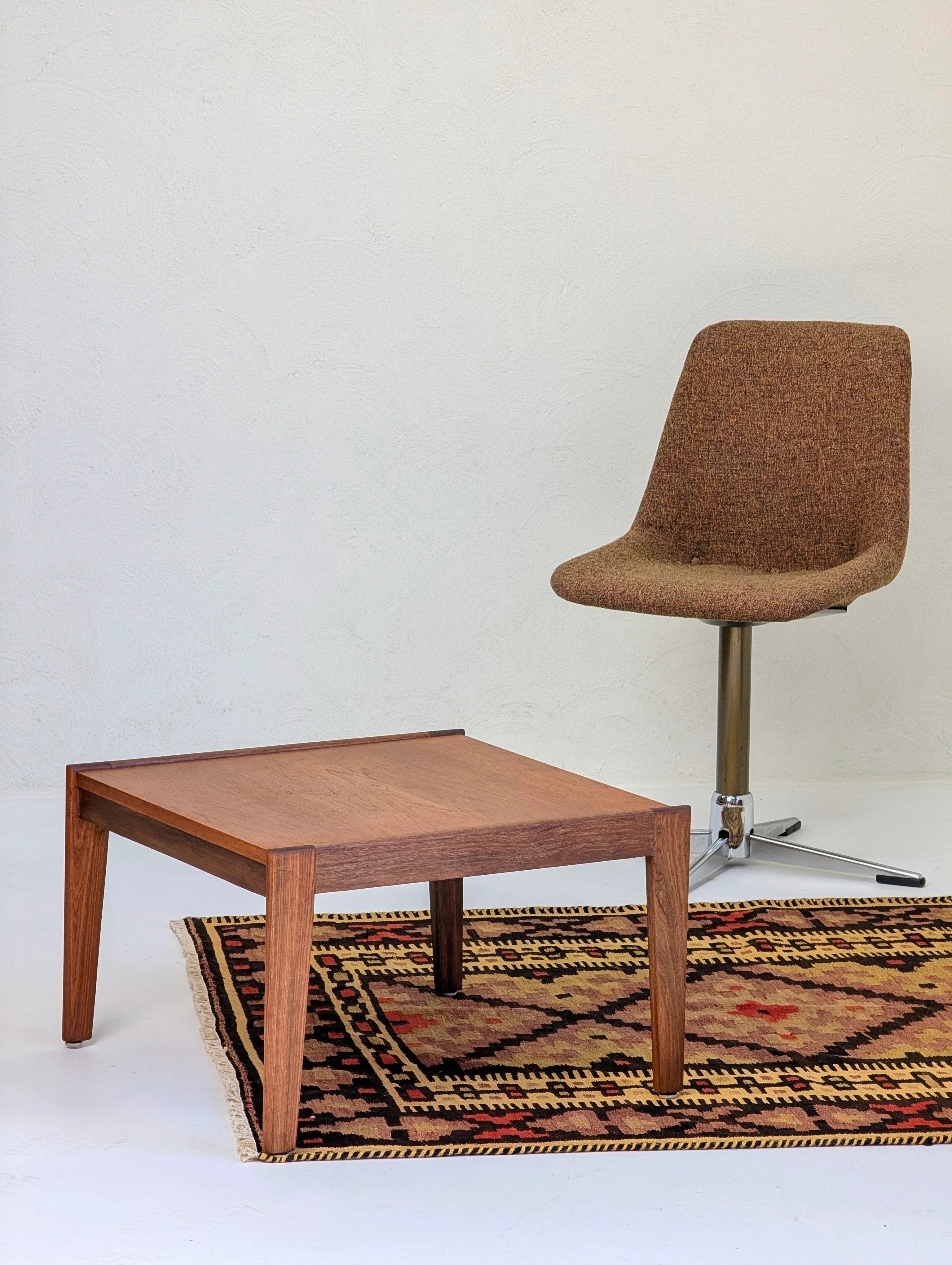 Mid-century modern brown upholstered swivel chair next to wooden coffee table on patterned rug