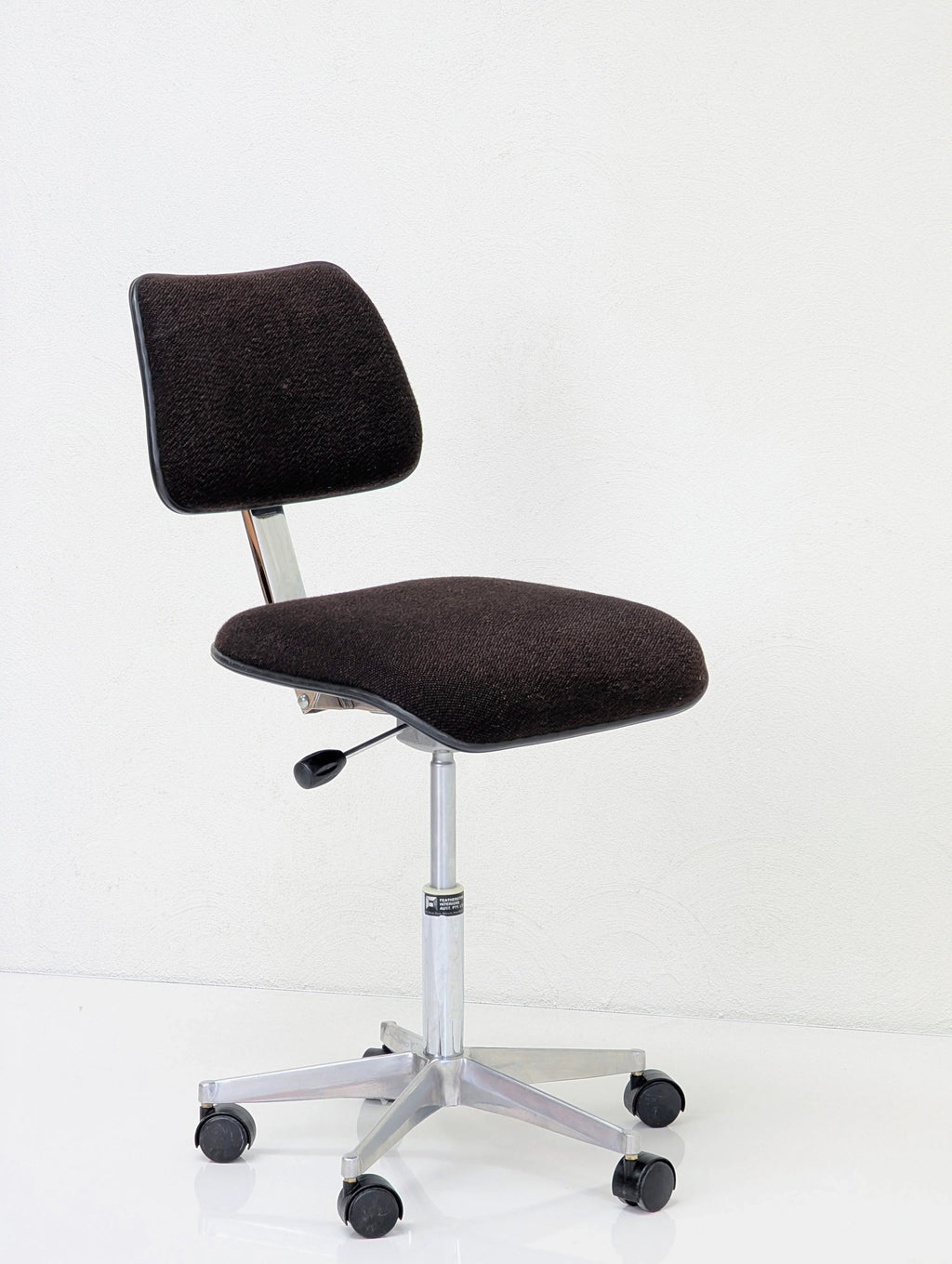 Black fabric cushioned office chair with adjustable height and caster wheels on white background