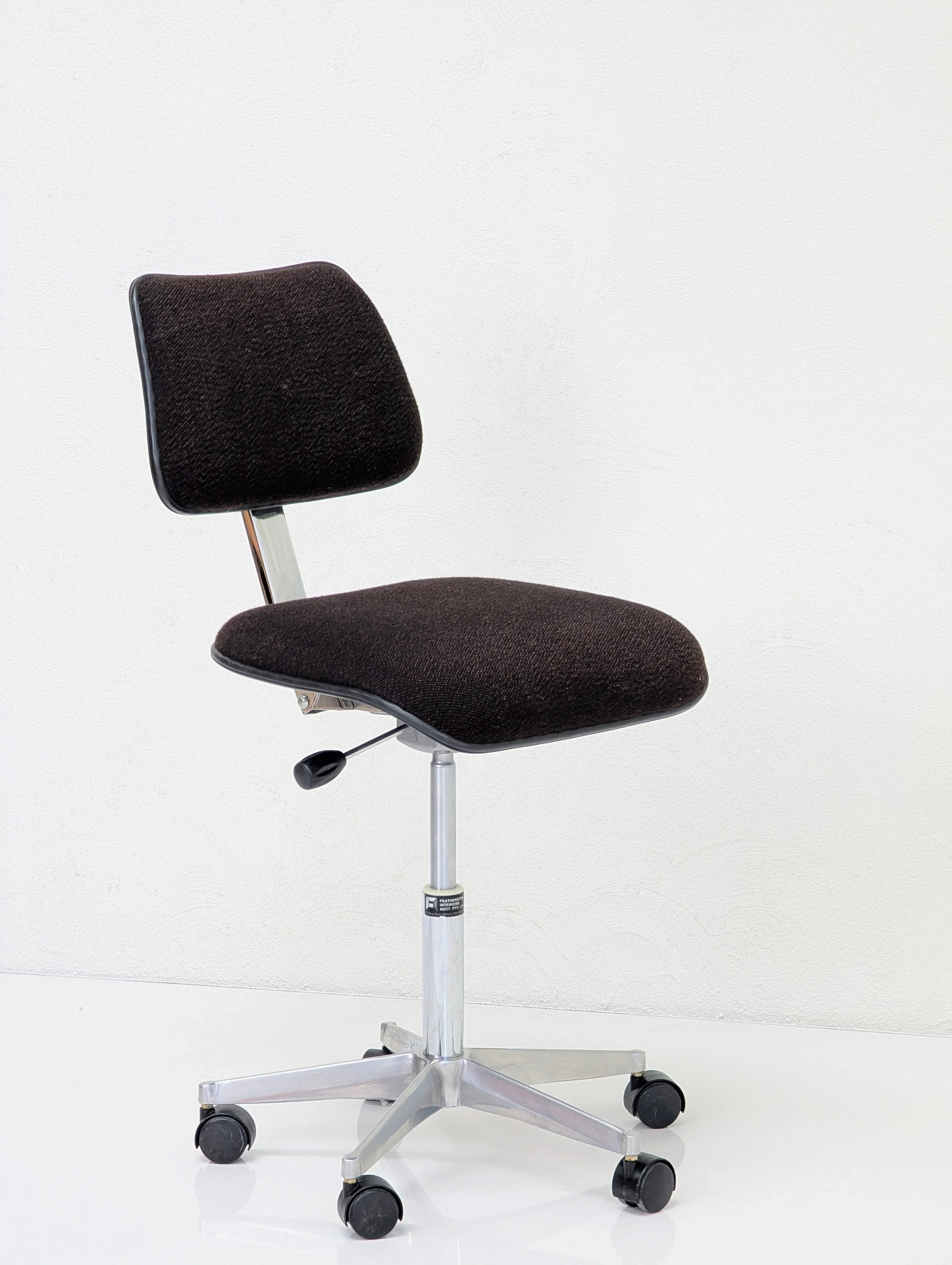 Black fabric cushioned office chair with adjustable height and caster wheels on white background