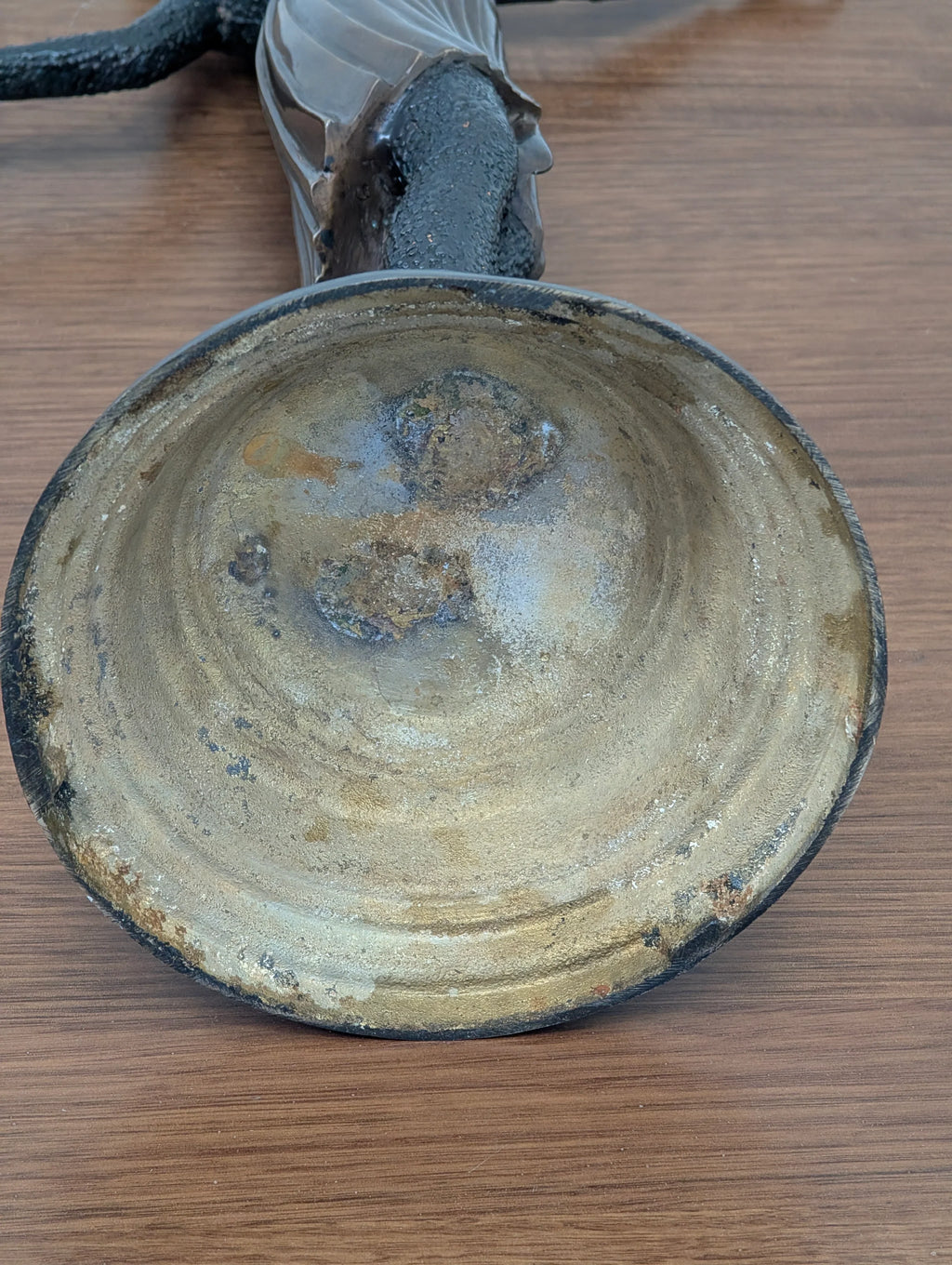 Rusty vintage metal frying pan with textured handle on wooden surface