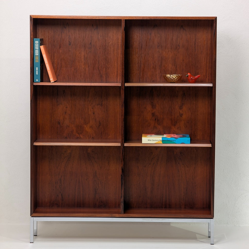 Mid-century modern wooden bookshelf with metal legs, displaying books and decorative items